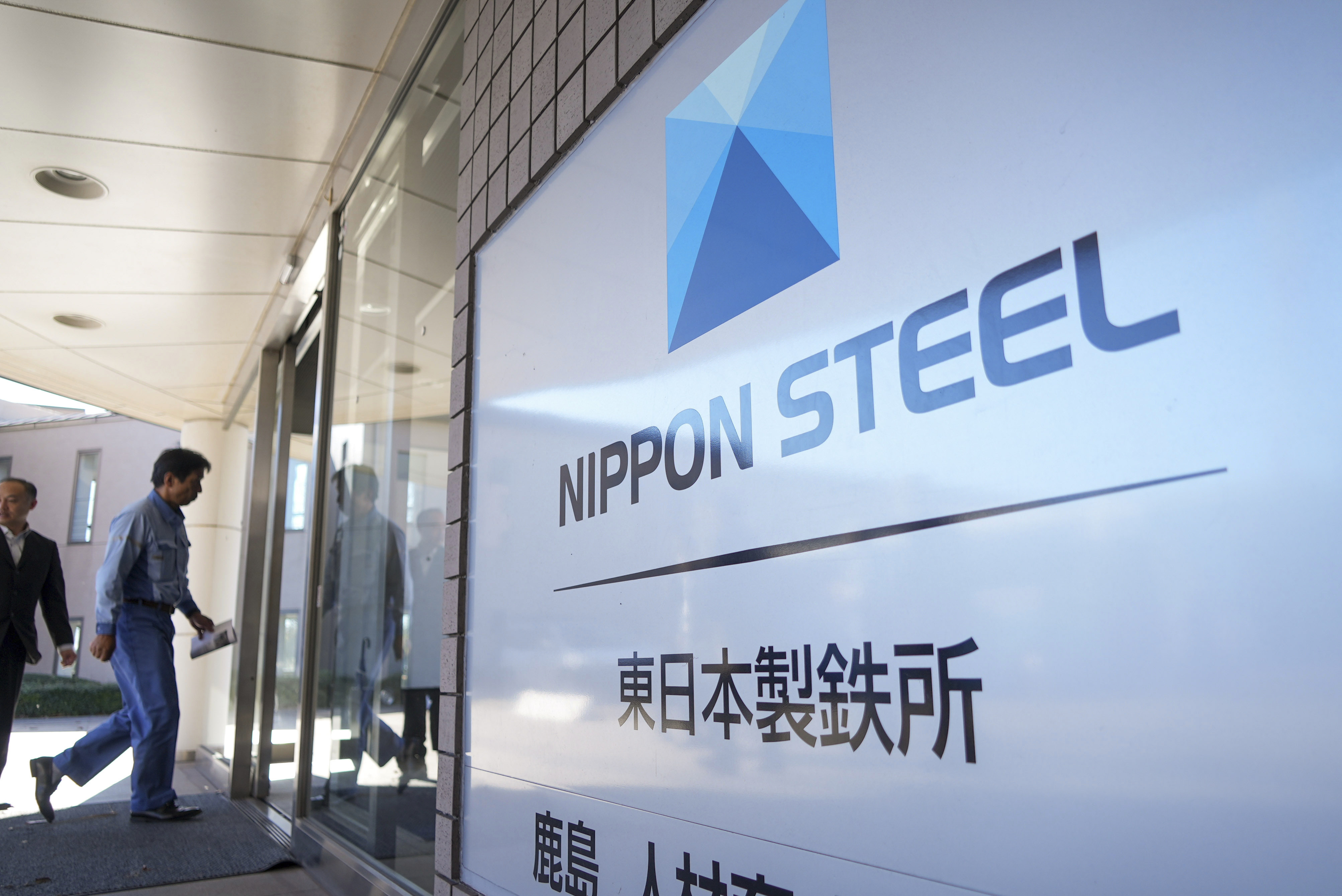 A staff enters doorway next to Nippon Steel logo at the company's Kashima Plant in Kashima, Japan on Friday, Dec. 6, 2024. (AP Photo/Ayaka McGill)