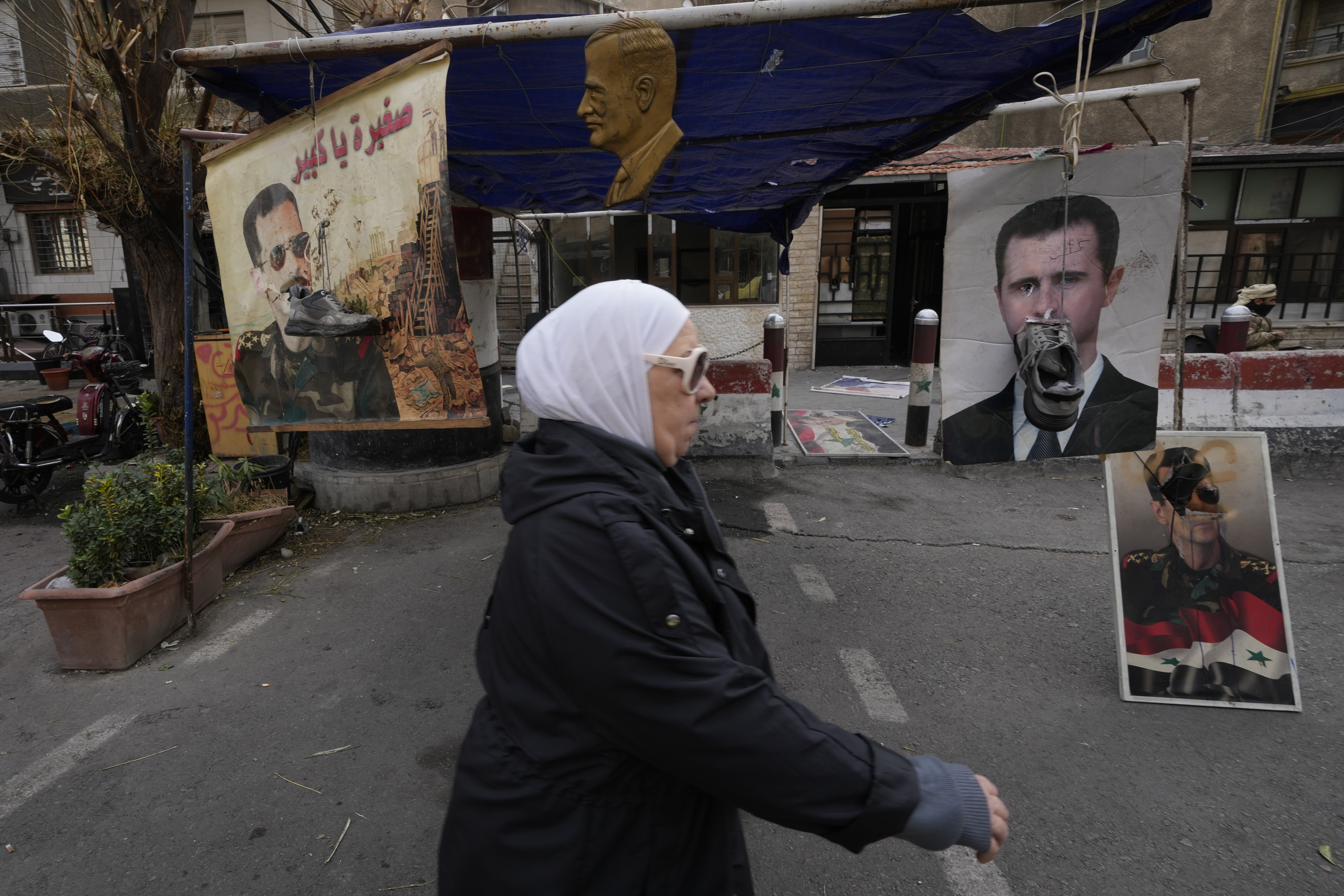 Shoes hanging in front of portraits of ousted Syrian President Bashar Assad in Damascus, Syria, Monday, Dec. 23, 2024. (AP Photo/Hussein Malla)