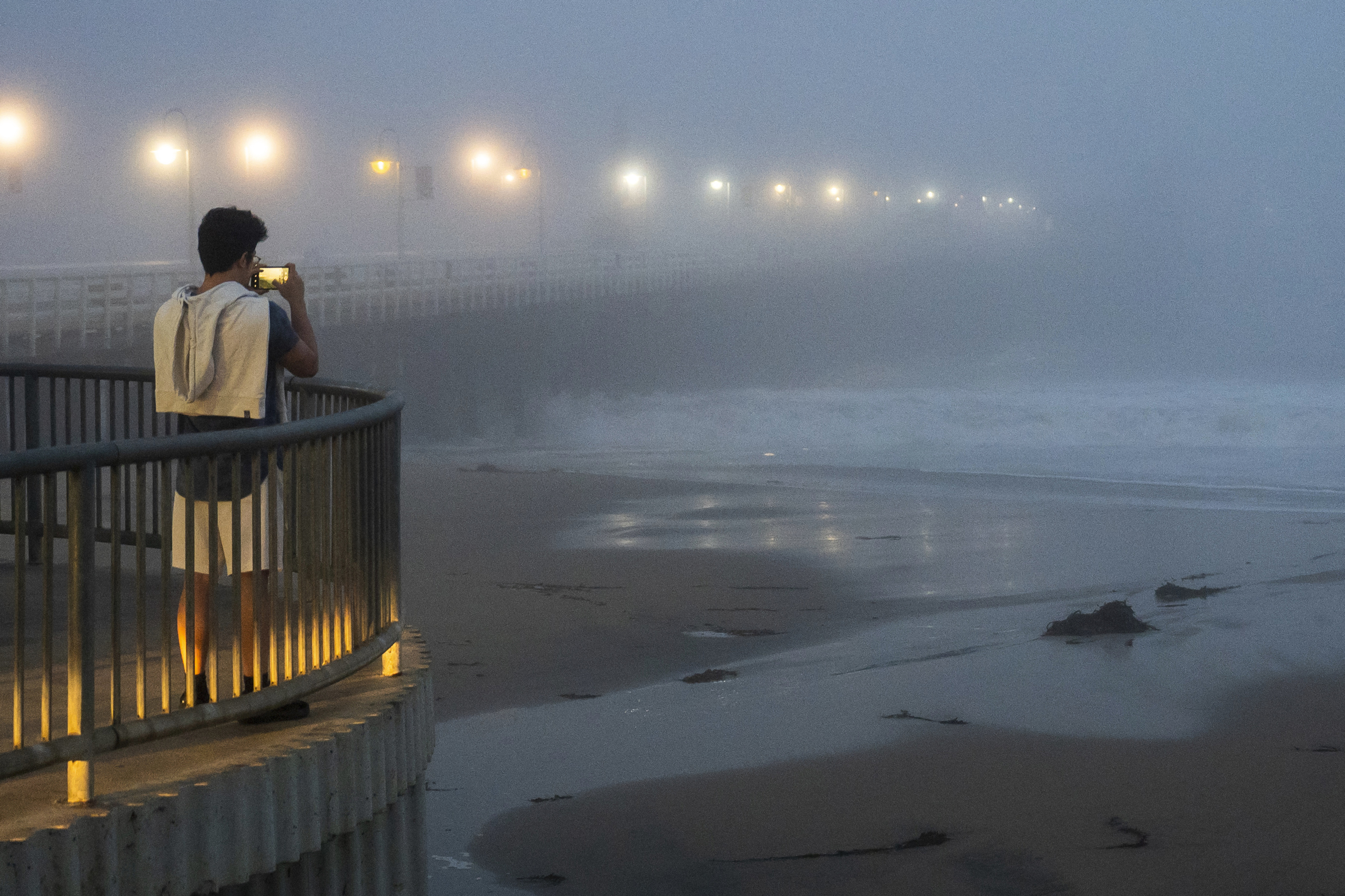 A person takes a photo of high surf near the Santa Cruz Wharf in Santa Cruz, Calif., Monday, Dec. 23, 2024. (AP Photo/Nic Coury)