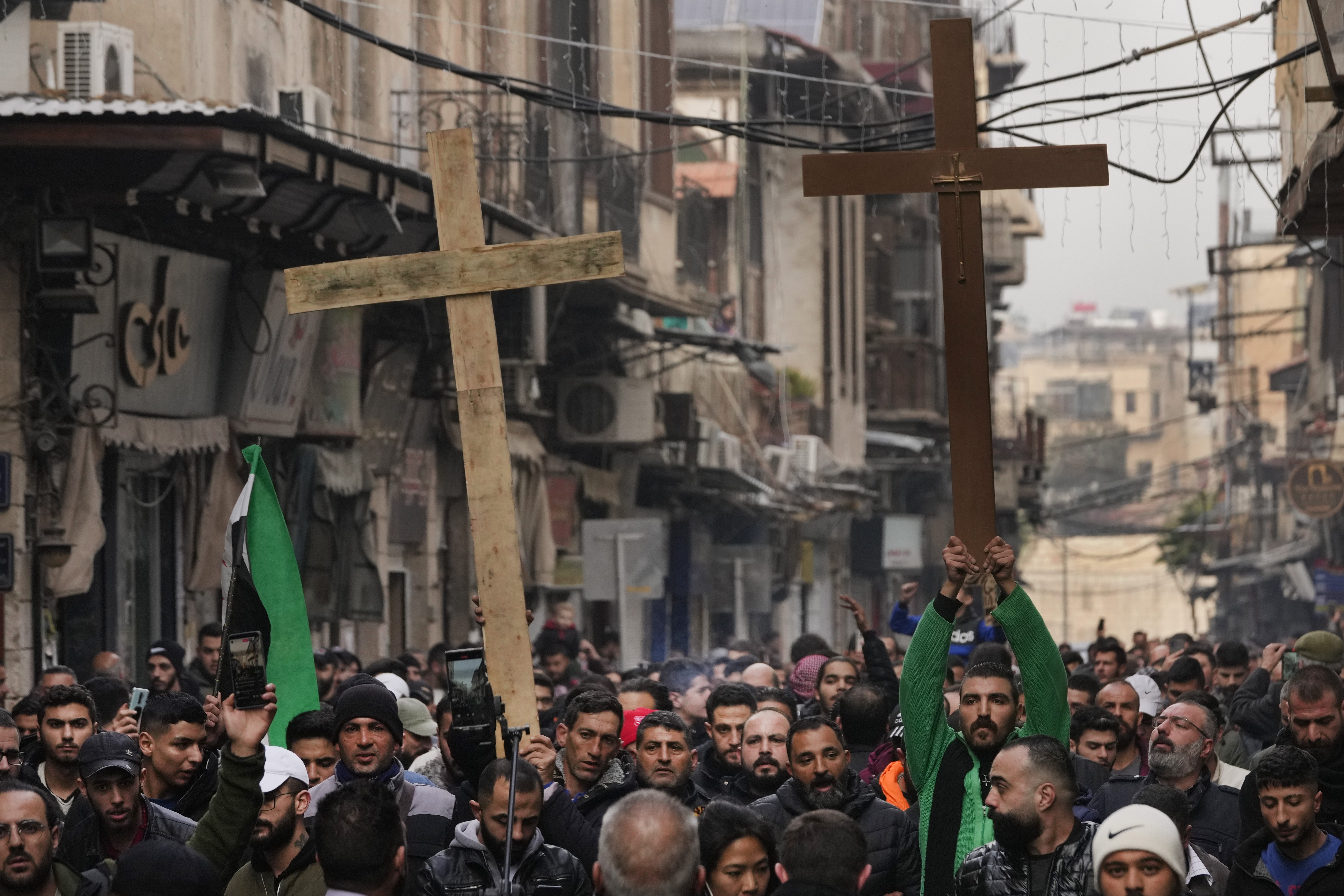 Syrian Christians hold up crosses and shout slogans in Damascus, Syria, Tuesday, Dec. 24, 2024 as they march during a protest after a Christmas tree was set on fire in Hamah city on Sunday. (AP Photo/Hussein Malla)