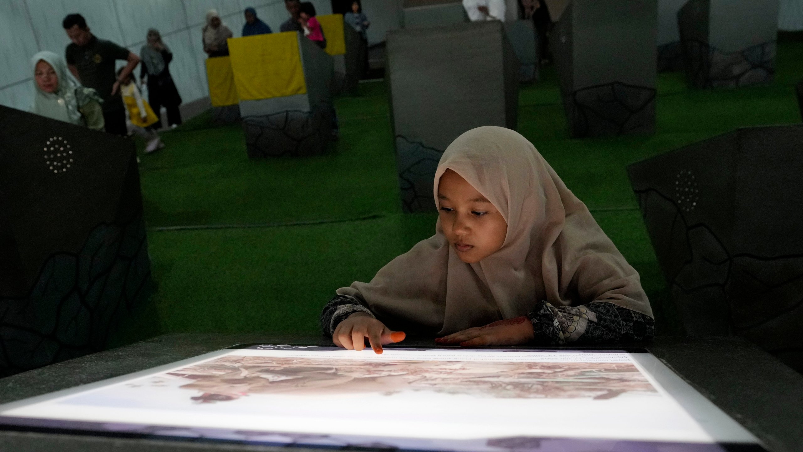 A young girl looks at a photo displayed at the Tsunami Museum in Banda Aceh, Indonesia, Saturday, Dec 14, 2024. (AP Photo/Achmad Ibrahim)