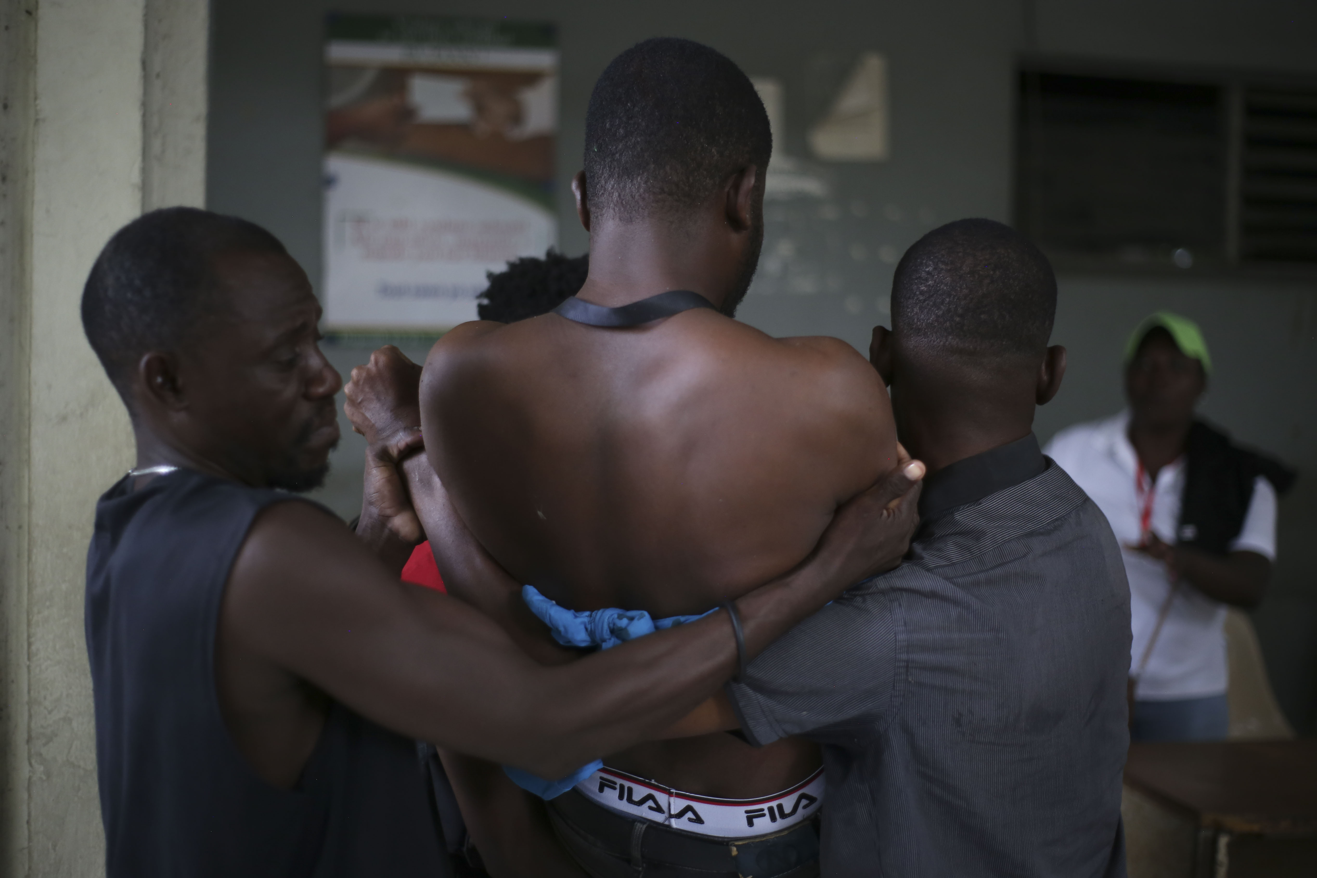 People help a wounded journalist who was shot by armed gangs at the General Hospital in Port-au-Prince, Haiti, Tuesday, Dec. 24, 2024. (AP Photo/Jean Feguens Regala)