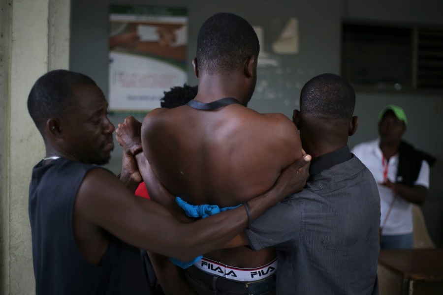 People help a wounded journalist who was shot by armed gangs at the General Hospital in Port-au-Prince, Haiti, Tuesday, Dec. 24, 2024. (AP Photo/Jean Feguens Regala)