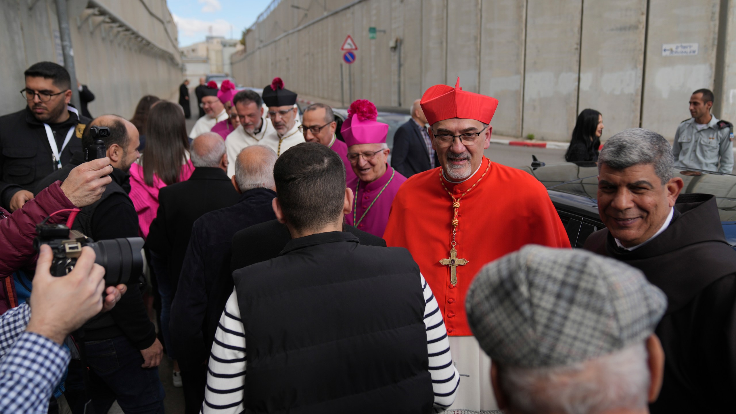 Archbishop Pierbattista Pizzaballa, the top Roman Catholic cleric in the Holy Land, is received by local community while crossing an Israeli military checkpoint from Jerusalem for Christmas Eve celebrations at the Church of the Nativity, traditionally recognized by Christians to be the birthplace of Jesus Christ, in the West Bank city of Bethlehem Tuesday, Dec. 24, 2024. (AP Photo/Nasser Nasser)