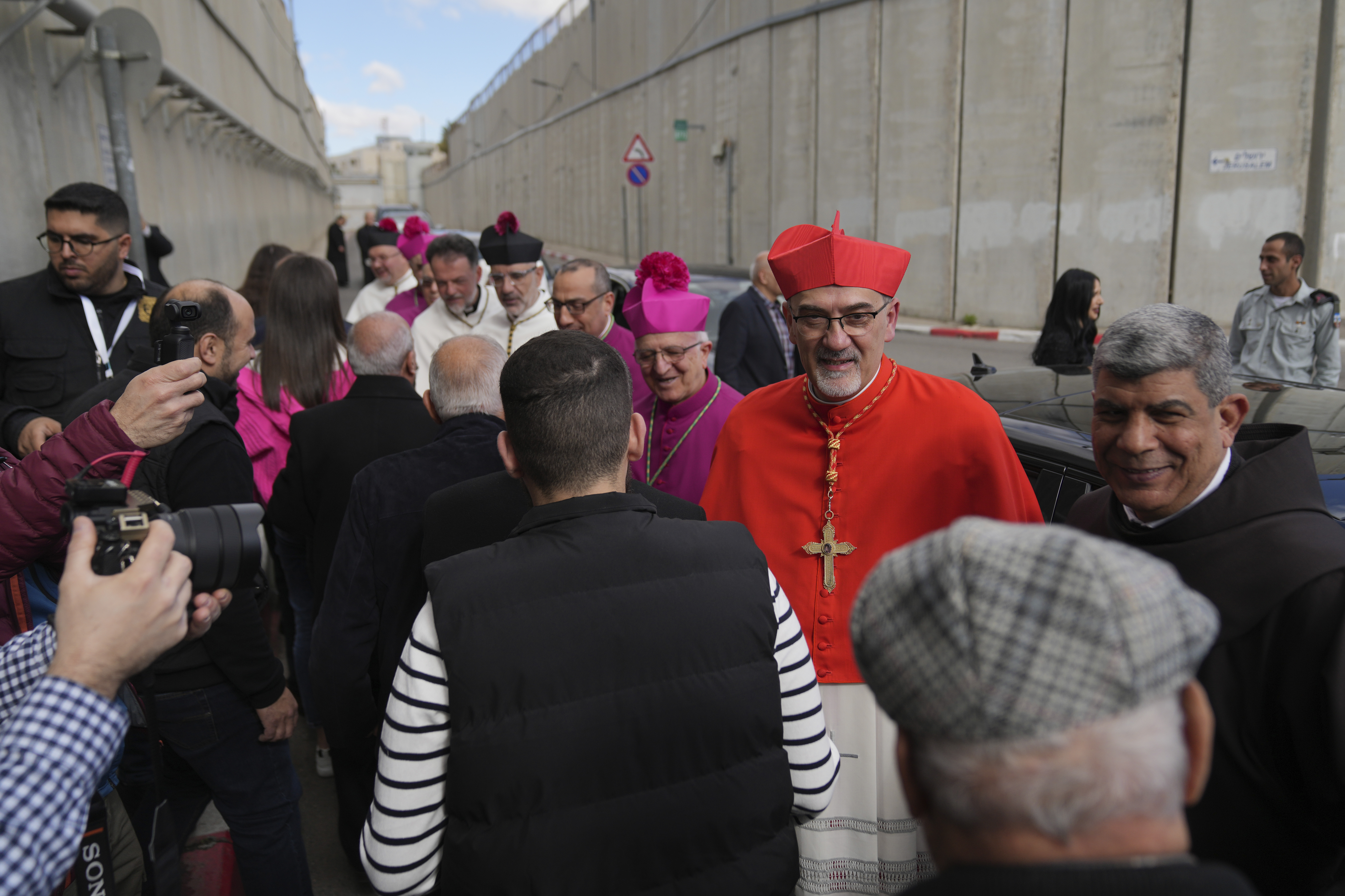 Archbishop Pierbattista Pizzaballa, the top Roman Catholic cleric in the Holy Land, is received by local community while crossing an Israeli military checkpoint from Jerusalem for Christmas Eve celebrations at the Church of the Nativity, traditionally recognized by Christians to be the birthplace of Jesus Christ, in the West Bank city of Bethlehem Tuesday, Dec. 24, 2024. (AP Photo/Nasser Nasser)