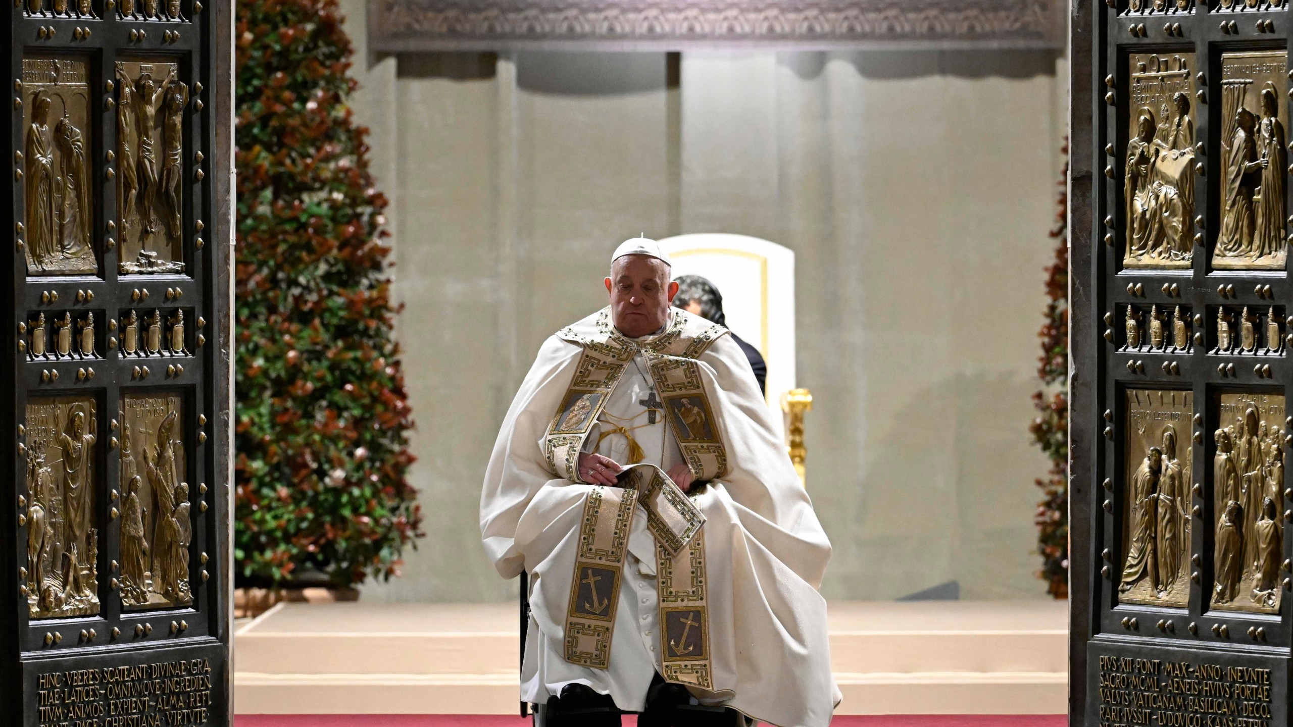 In this image released by Vatican Media, Pope Francis opens the holy door marking the start of the Catholic jubilar year 2025 before presiding over the Christmas Eve Mass in St. Peter's Basilica at The Vatican, Tuesday, Dec. 24, 2024. (AP Photo/Vatican Media, HO)