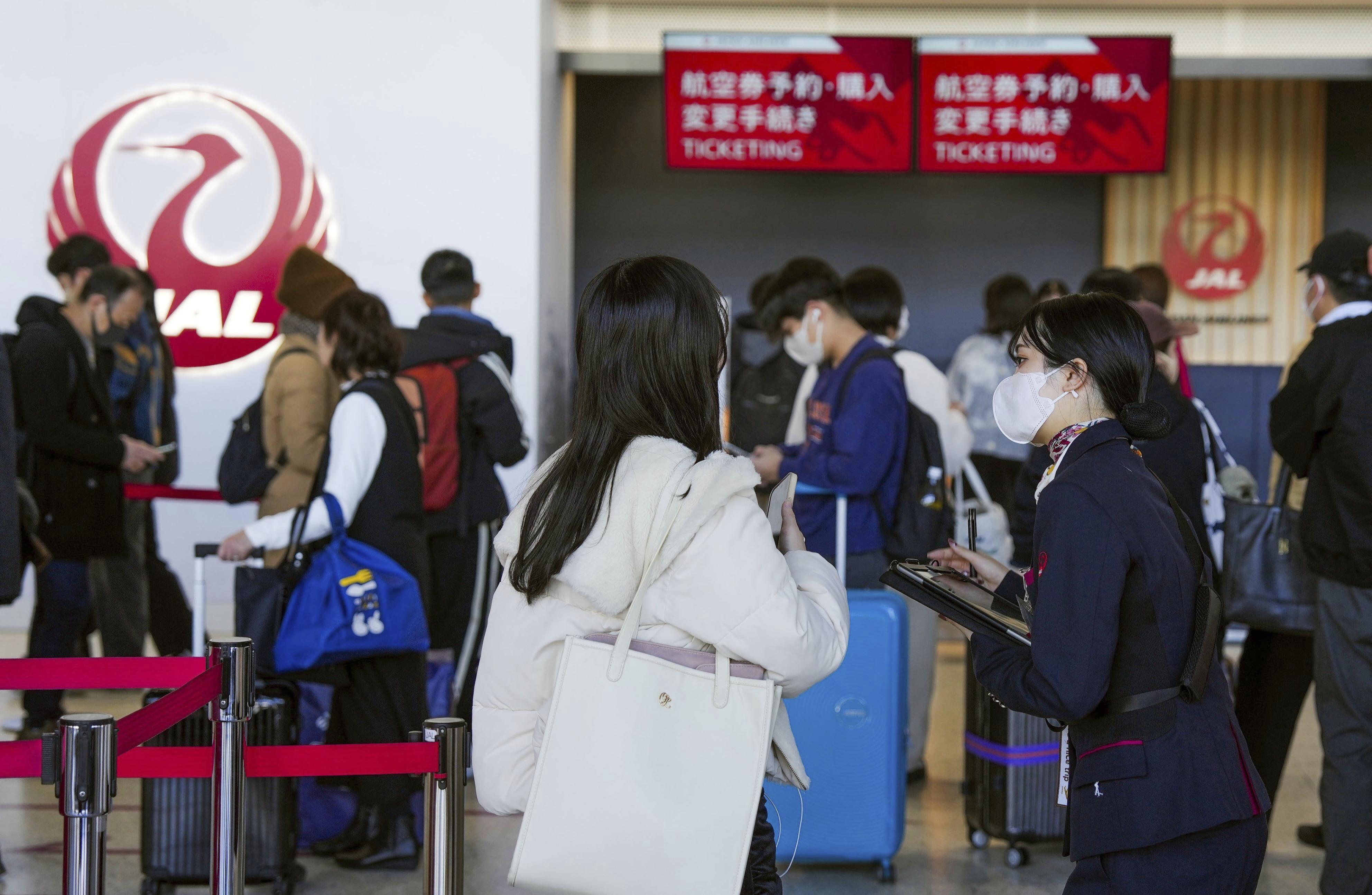 A staff member of Japan Airlines helps customers at Osaka International Airport on the outskirts of Osaka, western Japan, Thursday, Dec. 26, 2024, after the airlines said it was hit by a cyberattack. (Nobuki Ito/Kyodo News via AP)