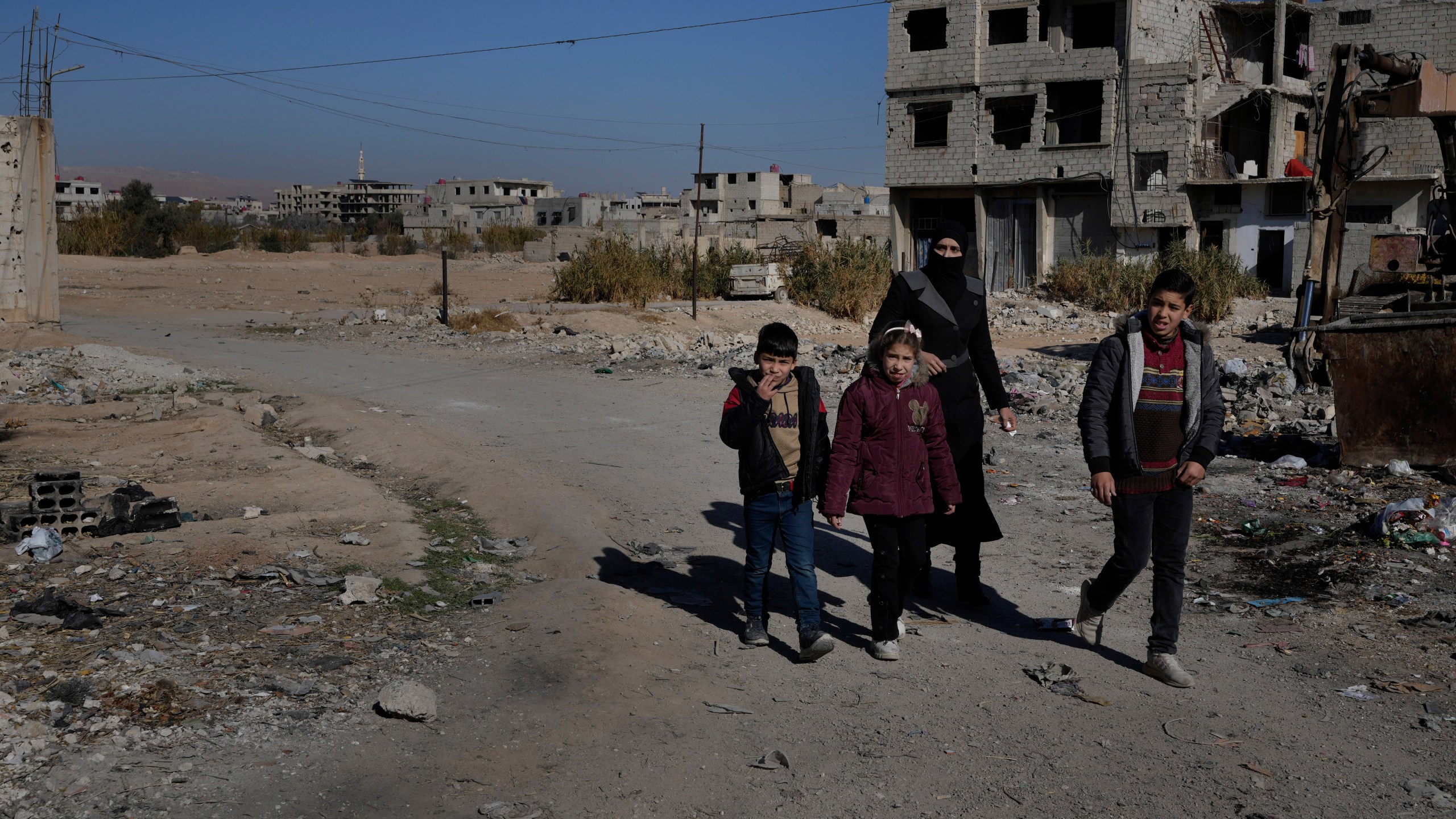 A Syrian family pass at an alley that was hit by the sarin struck during a 2013 chemical weapons attack that was blamed on then President Bashar Assad's forces, in Zamalka neighbourhood, on the outskirts of Damascus, Syria, Wednesday, Dec. 25, 2024. (AP Photo/Hussein Malla)