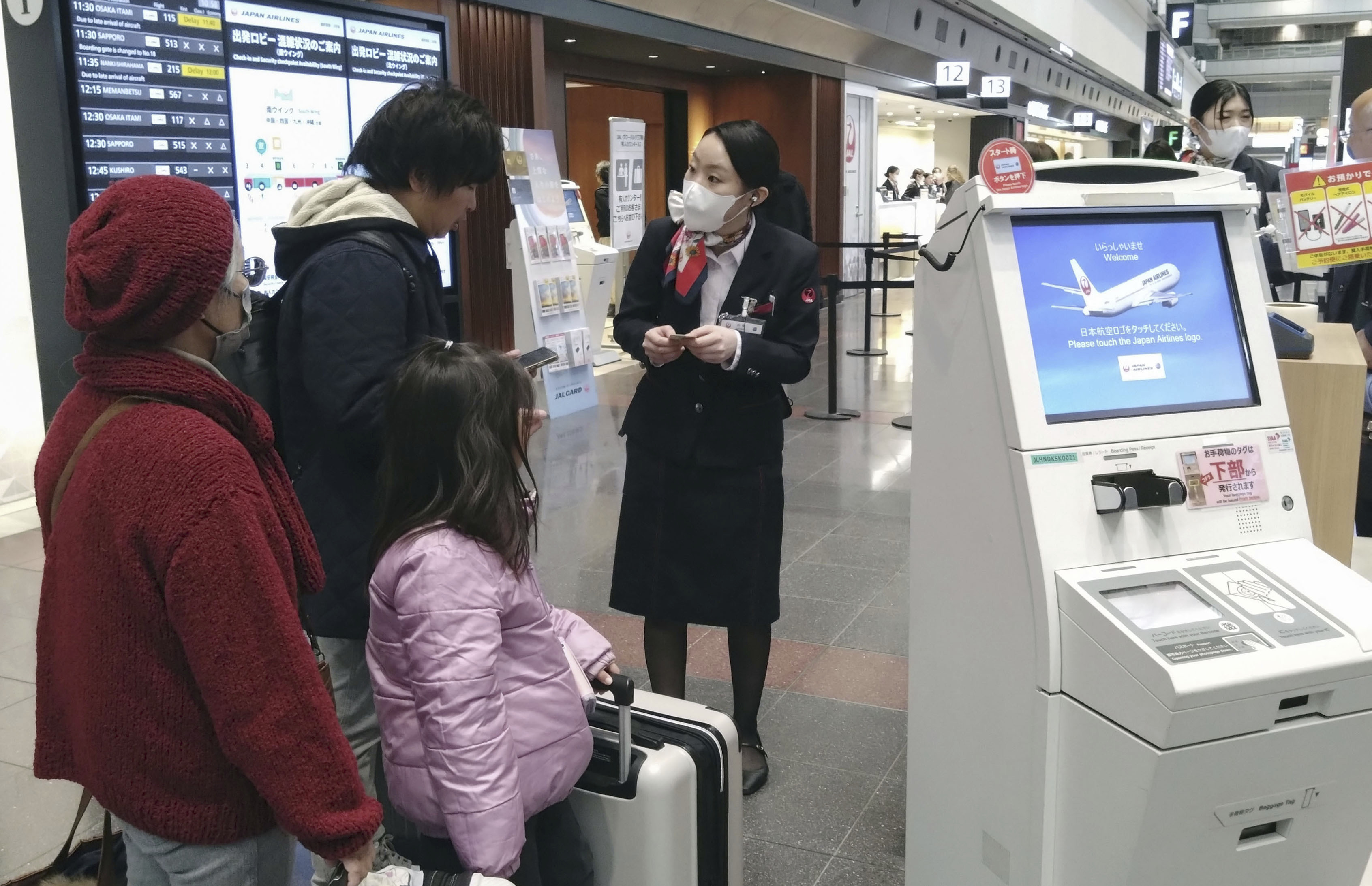 A staff member of Japan Airlines helps customers at the Haneda airport in Tokyo, Thursday, Dec. 26, 2024, after the airlines said it was hit by a cyberattack. (Shingo Fukuma/Kyodo News via AP)