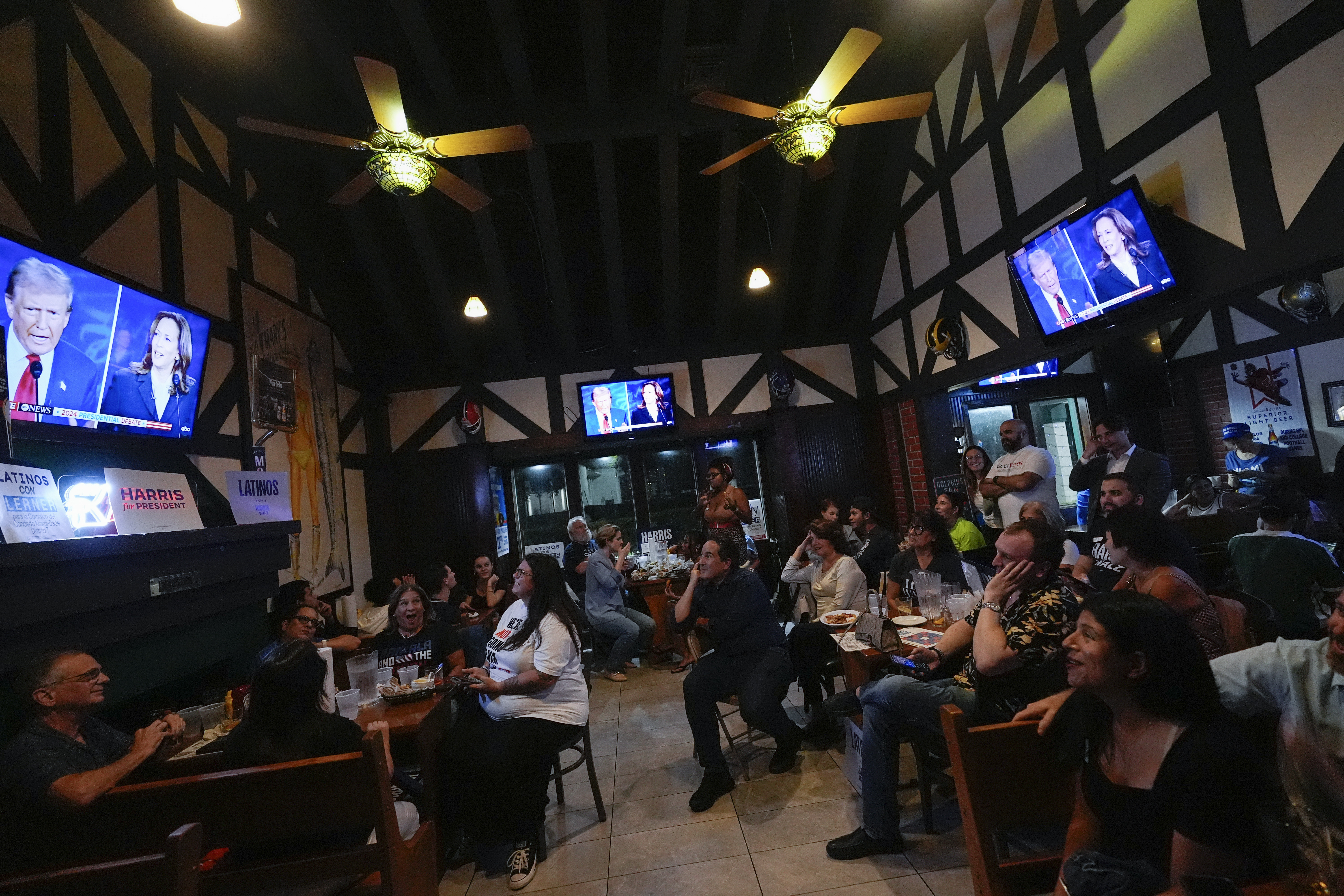 FILE - People watch TV screens showing a debate between Democratic presidential nominee Vice President Kamala Harris, right on screen, and Republican presidential nominee former President Donald Trump, at Sports Grill Kendall, where the Miami-Dade Democratic Hispanic Caucus had organized a watch party, Tuesday, Sept. 10, 2024, in Miami. (AP Photo/Rebecca Blackwell, File)