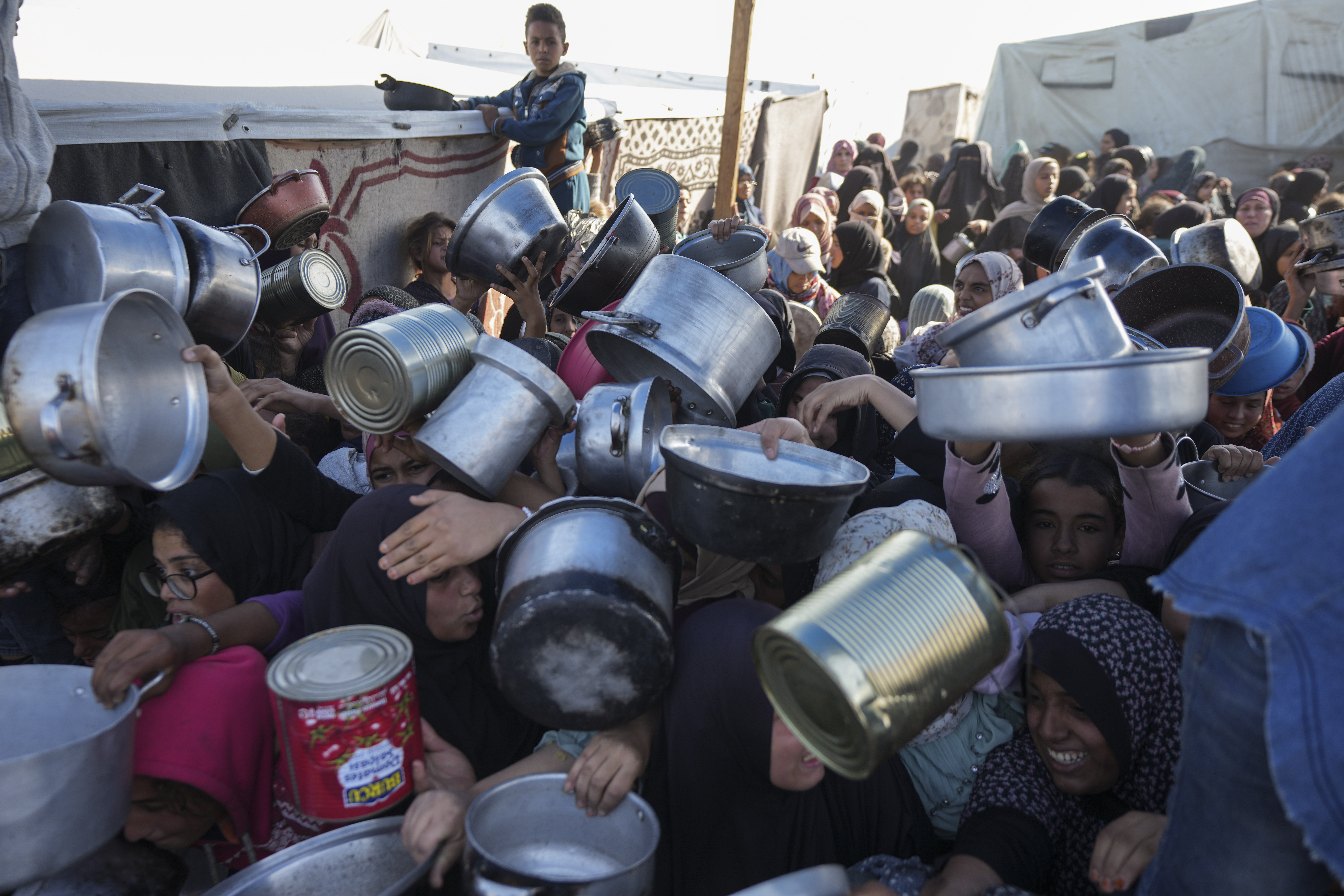 FILE - Palestinian women and girls struggle to reach for food at a distribution center in Khan Younis, Gaza Strip Friday, Dec. 6, 2024. (AP Photo/Abdel Kareem Hana, File)