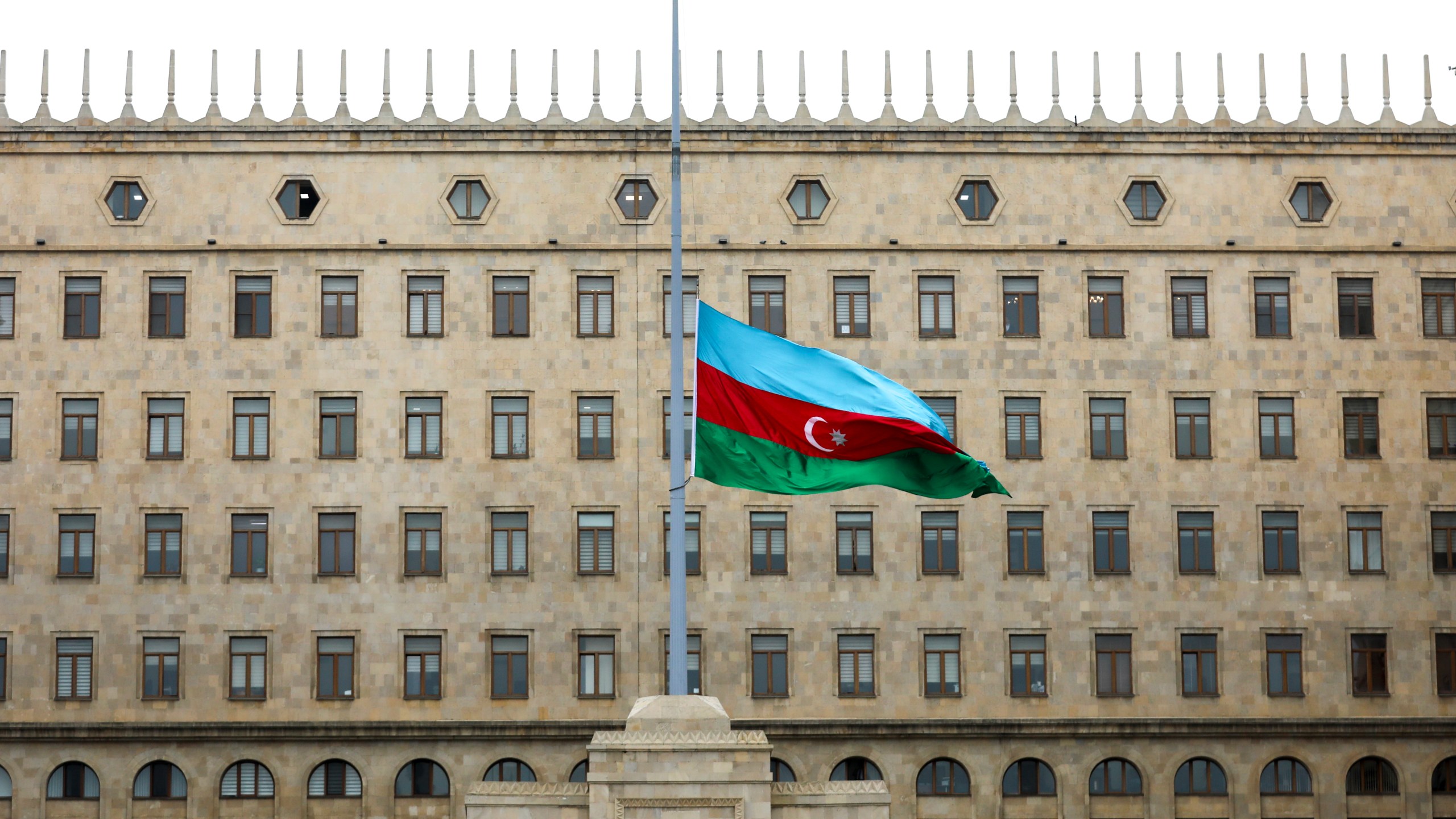 Azerbaijan's national flag at half-mast in the memory of victims of the Azerbaijan Airlines' Embraer 190 that crashed near the Kazakhstan's airport of Aktau, is seen in front of a Government's building in the center of Baku, Azerbaijan, Thursday, Dec. 26, 2024. (AP Photo/Aziz Karimov)