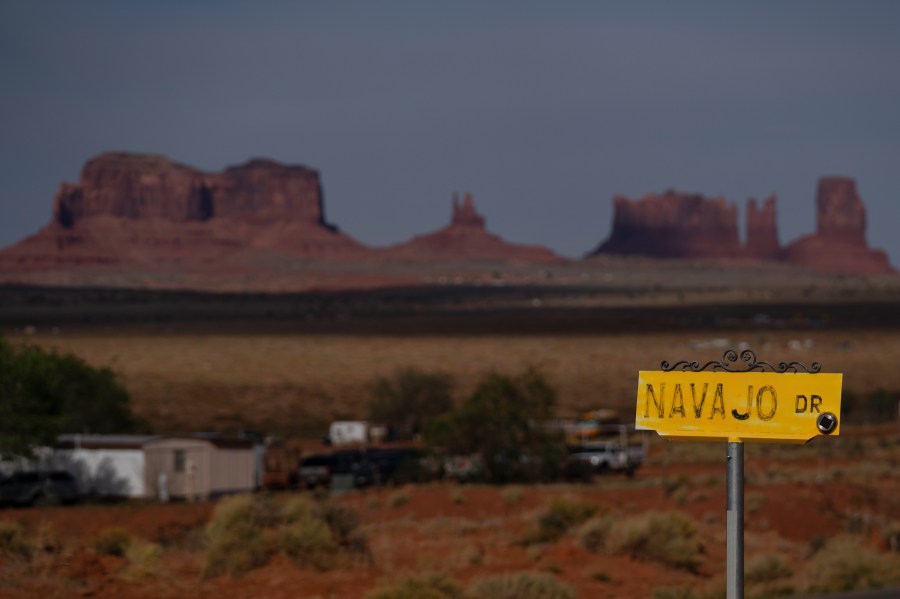 FILE - A sign marks Navajo Drive, as Sentinel Mesa stands in the distance in Oljato-Monument Valley, Utah on the Navajo Reservation, April 30, 2020. (AP Photo/Carolyn Kaster, File)