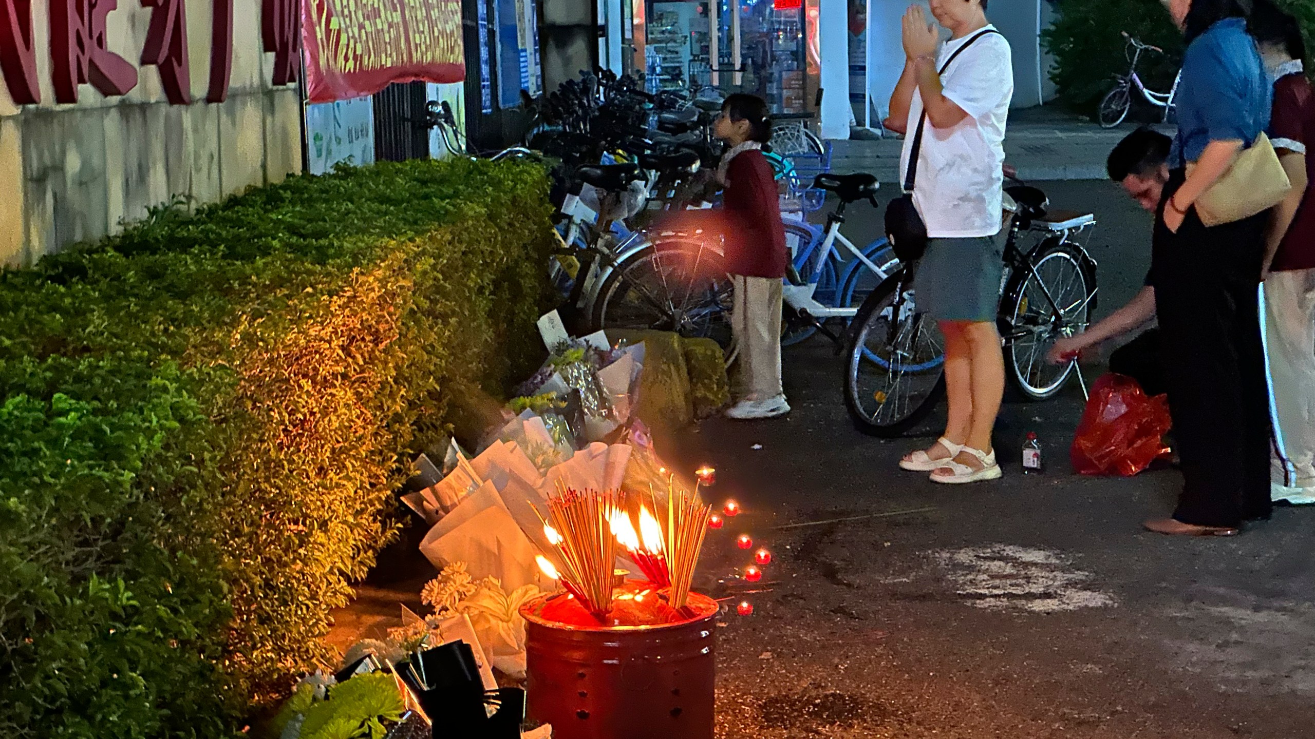 A woman prays after incense were offered near flowers placed outside the Zhuhai People's Fitness Plaza, where a man deliberately rammed his car into people exercising at the sports center, killing some and injuring others in Zhuhai in southern China's Guangdong province on Tuesday, Nov. 12, 2024. (AP Photo/Ng Han Guan, File)