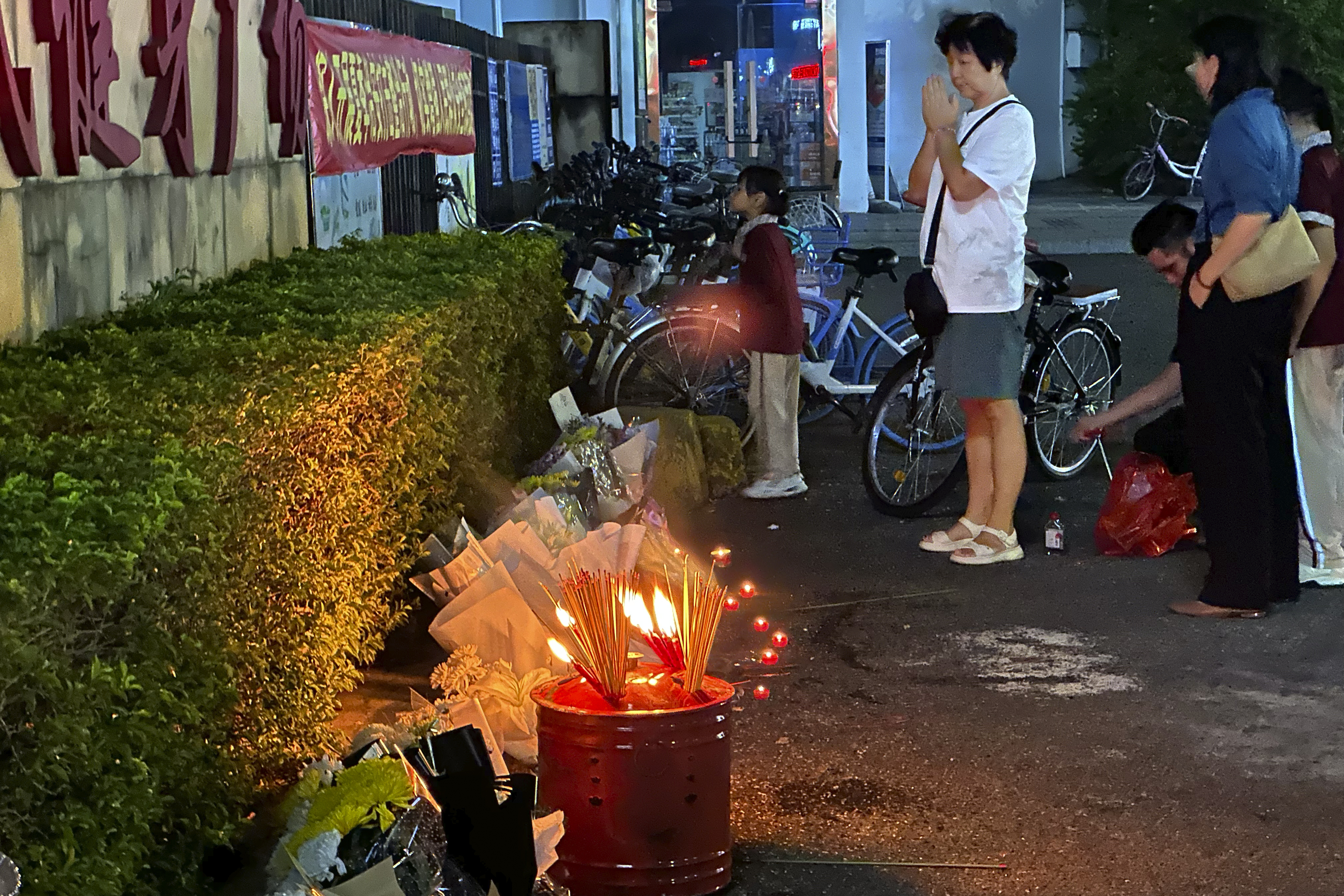 A woman prays after incense were offered near flowers placed outside the Zhuhai People's Fitness Plaza, where a man deliberately rammed his car into people exercising at the sports center, killing some and injuring others in Zhuhai in southern China's Guangdong province on Tuesday, Nov. 12, 2024. (AP Photo/Ng Han Guan, File)