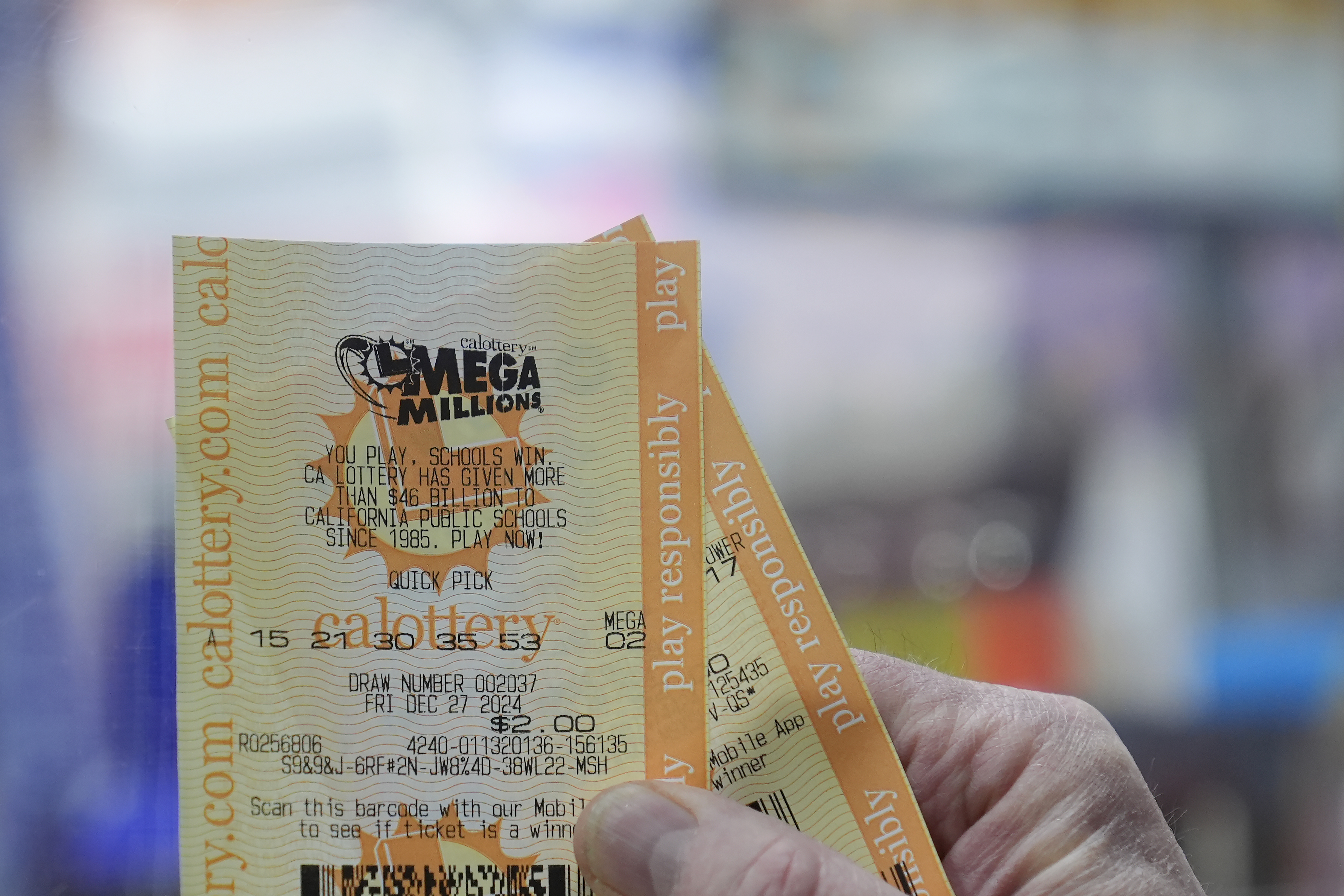 Rob holds up a Mega Millions ticket at Rossi's Deli in San Francisco, Thursday, Dec. 26, 2024. (AP Photo/Jeff Chiu)