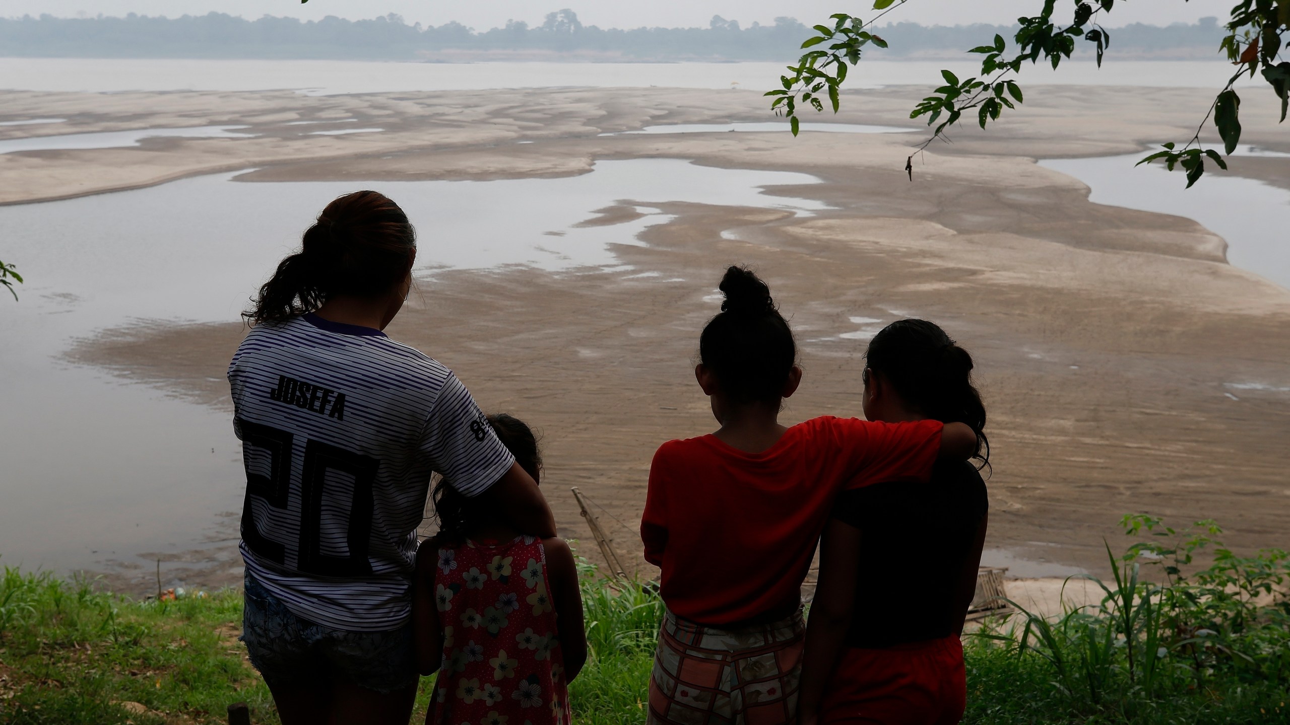 FILE - Residents look out at the Madeira River, a tributary of the Amazon River amid a drought in Humaita, Amazonas state, Brazil, Sept. 7, 2024. (AP Photo/Edmar Barros, File)