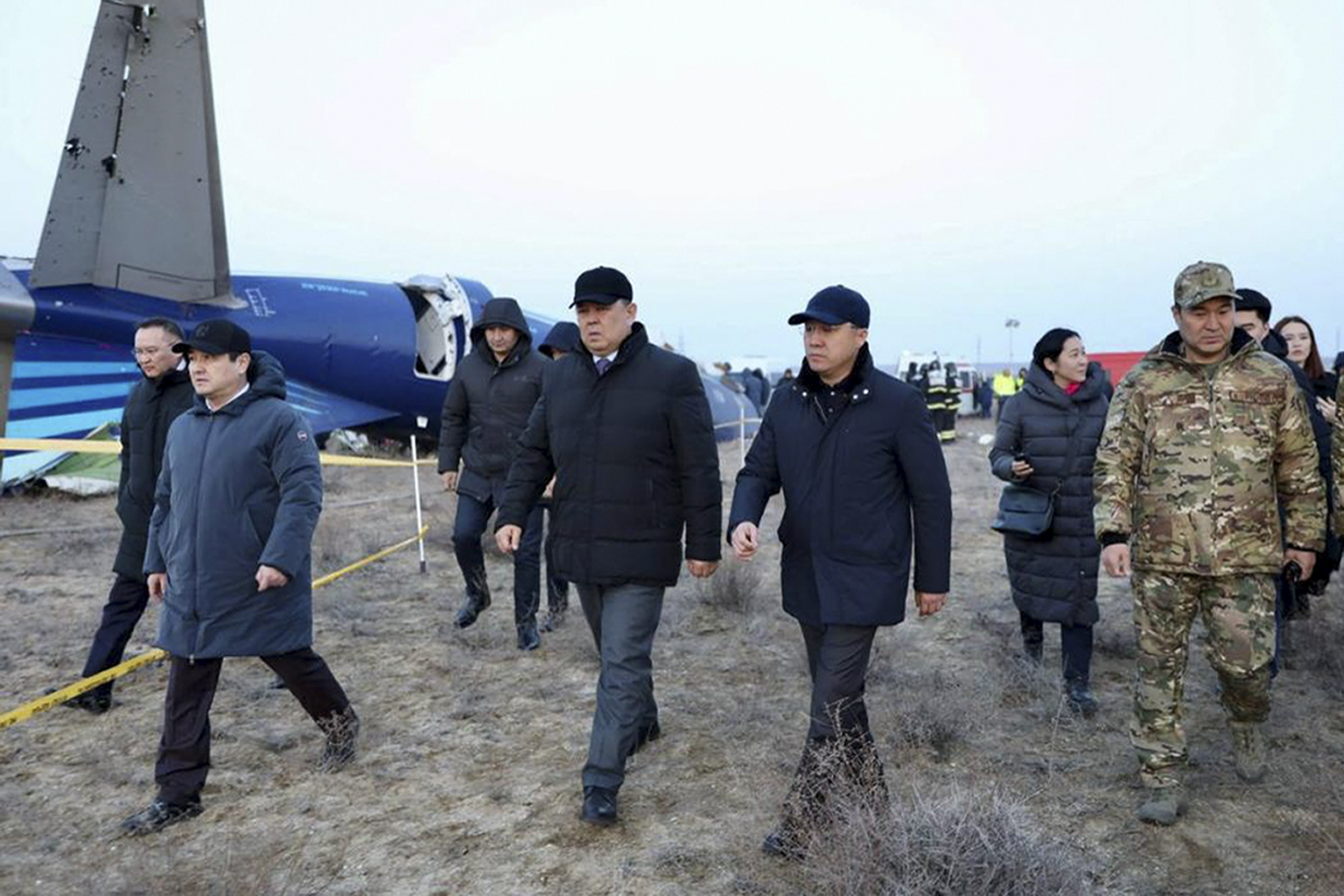 In this photo taken from a video released by the administration of Mangystau region, Members of an investigation committee and local officials walk past the wreckage of Azerbaijan Airlines' Embraer 190 lying on the ground near the airport of Aktau, Kazakhstan, on Thursday, Dec. 26, 2024. (The Administration of Mangystau Region via AP)