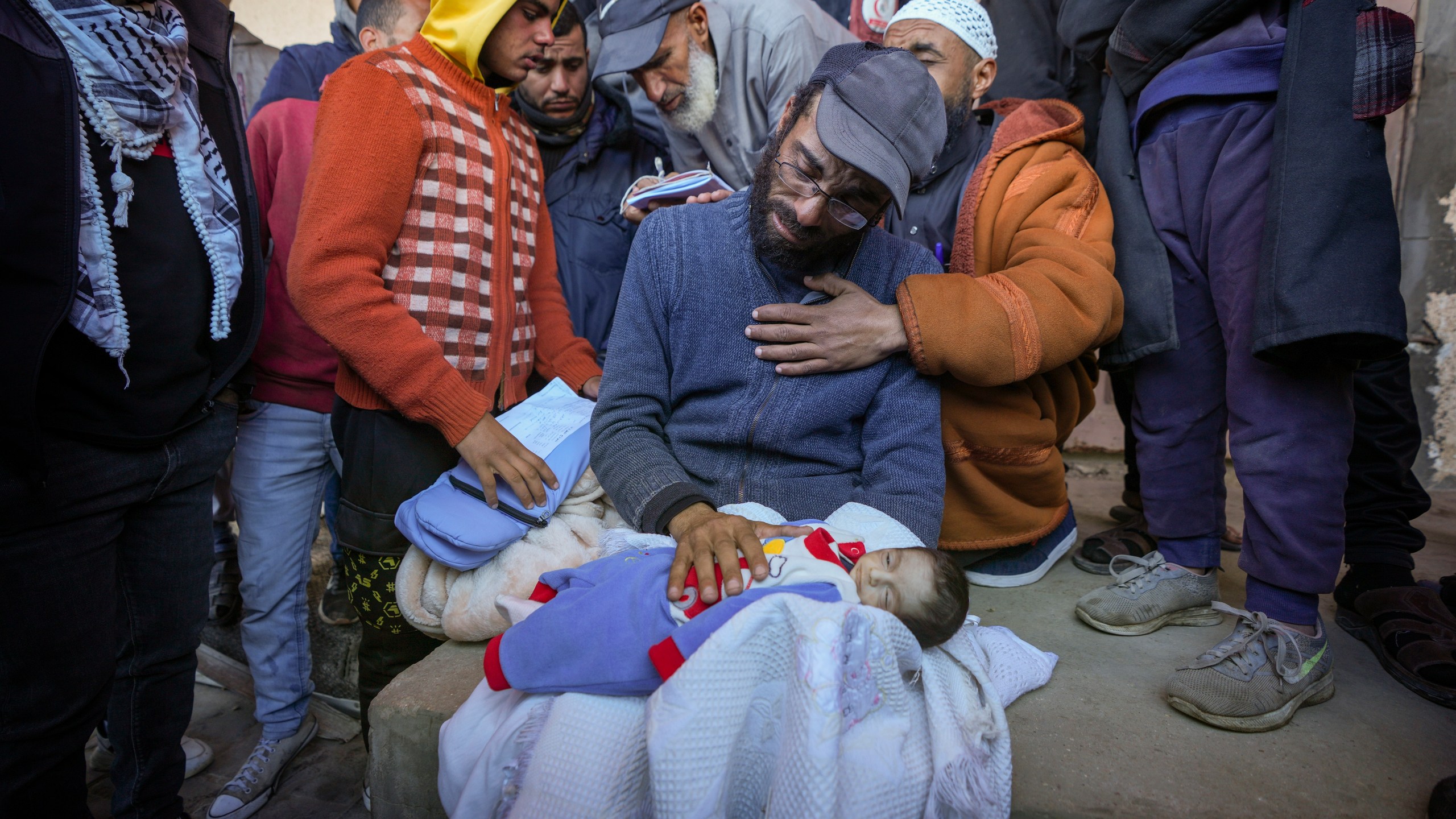 EDS NOTE: GRAPHIC CONTENT - Yehia al-Batran grieves as he holds the body of his 20-day-old son Jomaa, who died from hypothermia, at Al-Aqsa Martyrs Hospital in central Gaza, Sunday, Dec. 29, 2024. Jomaa's twin brother, Ali, remains in intensive care, as local health officials report at least three other infant deaths from the cold in recent weeks. (AP Photo/Abdel Kareem Hana)