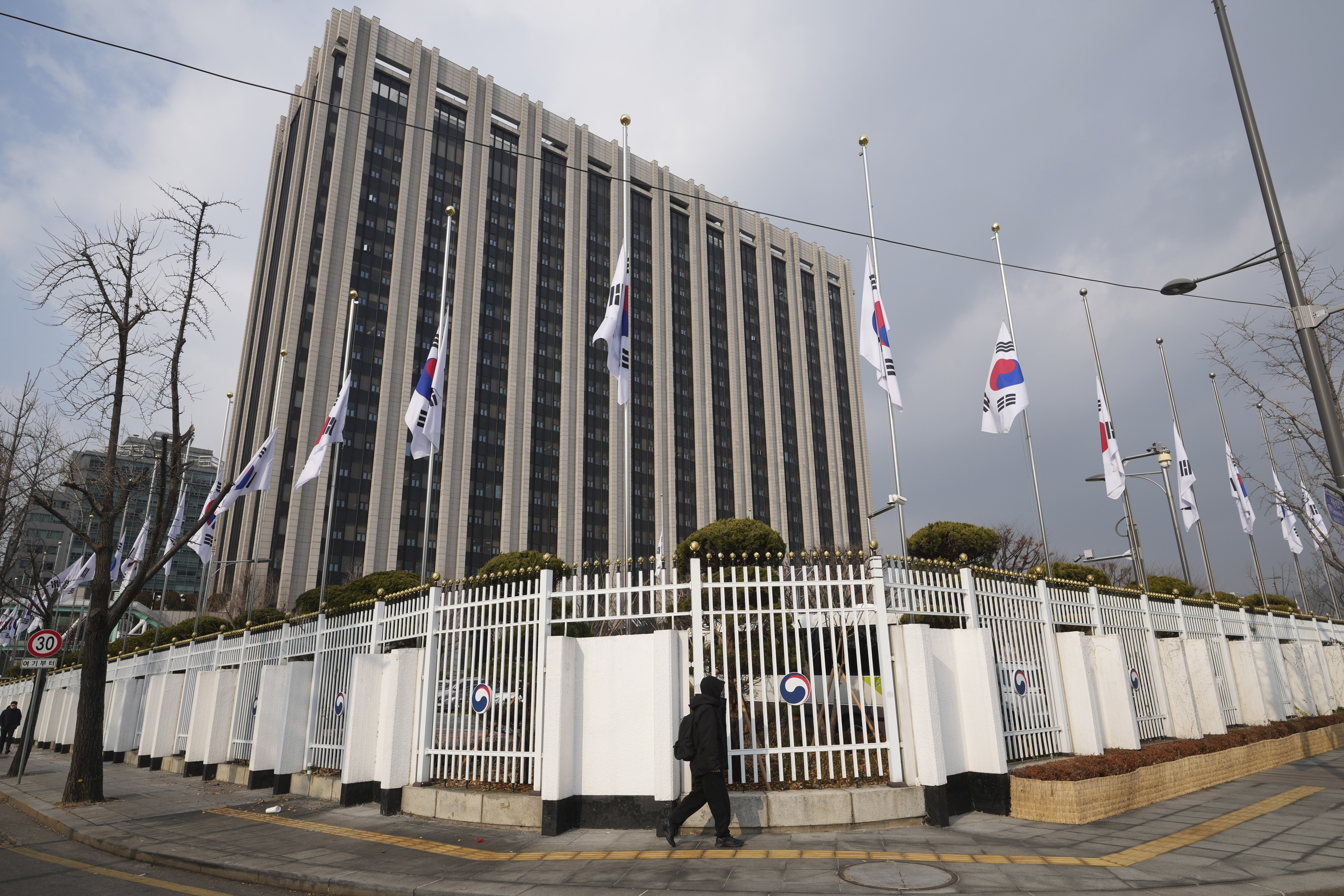 South Korean national flags fly at half-staff at a government complex in Seoul, South Korea, Monday, Dec. 30, 2024, a day after a jetliner skidded off a runway, slammed into a concrete fence and burst into flames at an airport the town of Muan. (AP Photo/Lee Jin-man)