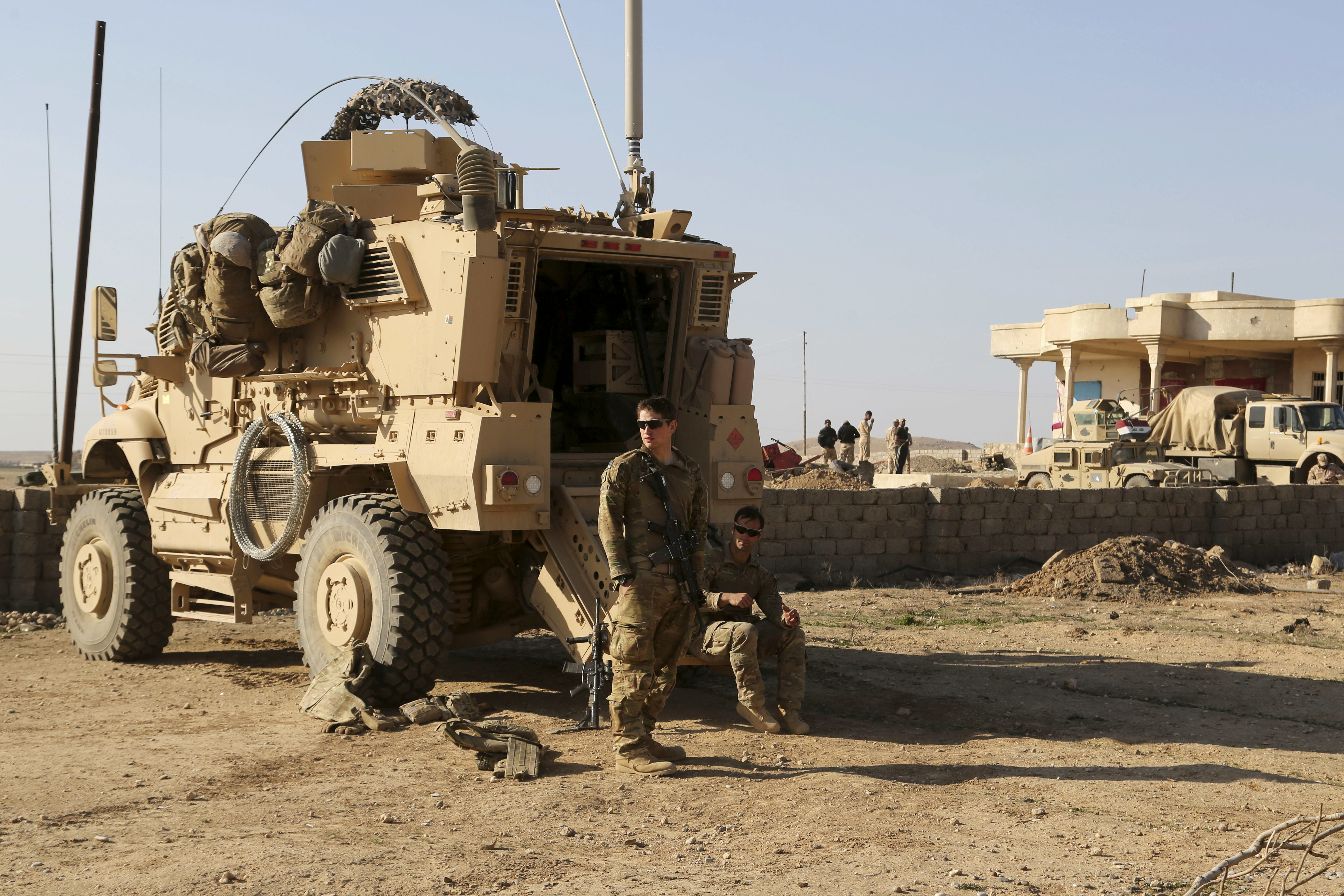 FILE - U.S. Army soldiers stand outside their armored vehicle on a joint base with the Iraqi army, south of Mosul, Iraq, Feb. 23, 2017. (AP Photo/ Khalid Mohammed, File)