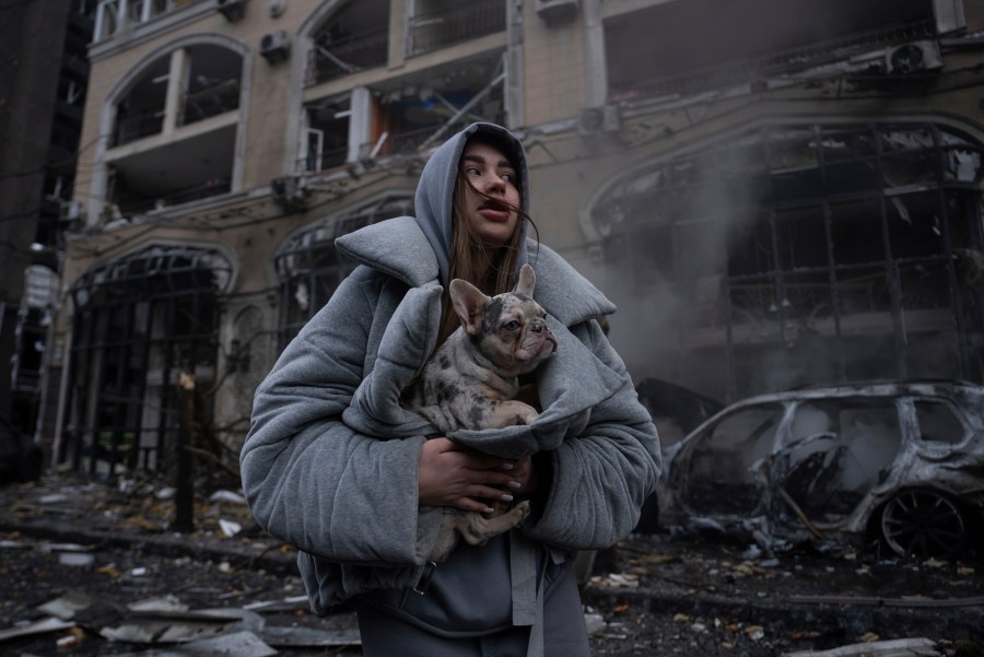 Ivanna, warms her dog in front of a destroyed burning car after a recent Russian attack in Kyiv, Ukraine, Friday, Dec. 20, 2024. (AP Photo/Alex Babenko)