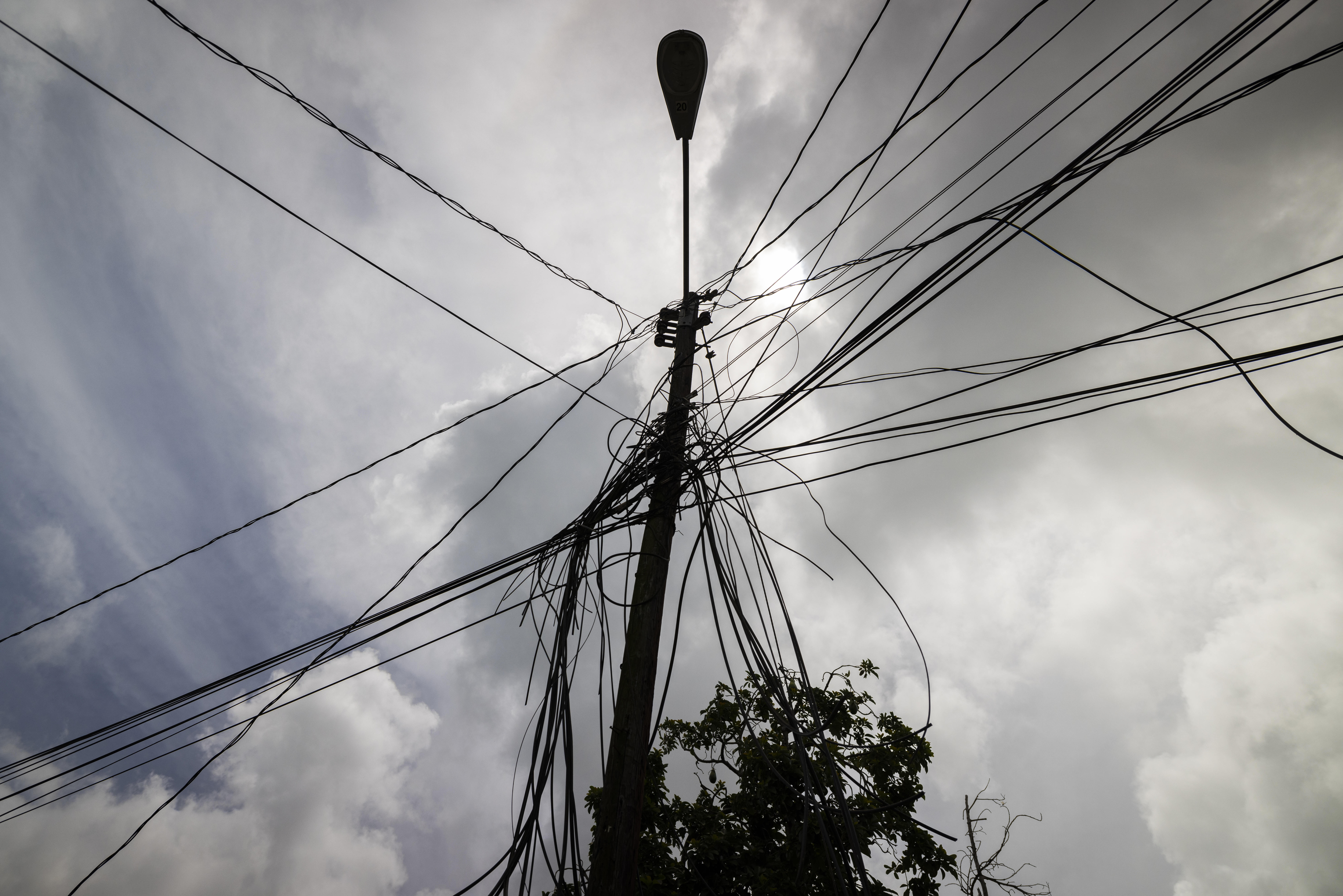 FILE - A utility pole with loose cables towers over a home in Loiza, Puerto Rico, Sept. 15, 2022. (AP Photo/Alejandro Granadillo, File)