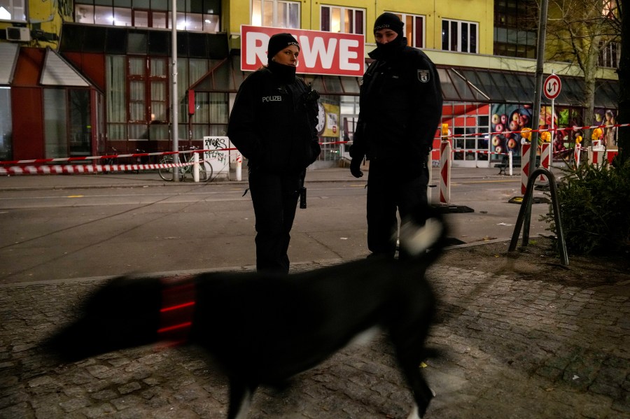 Police officers stand guard in front of a Rewe Market after a knife attack, in Berlin, Germany, Tuesday, Dec. 31, 2024. (AP Photo/Ebrahim Noroozi)