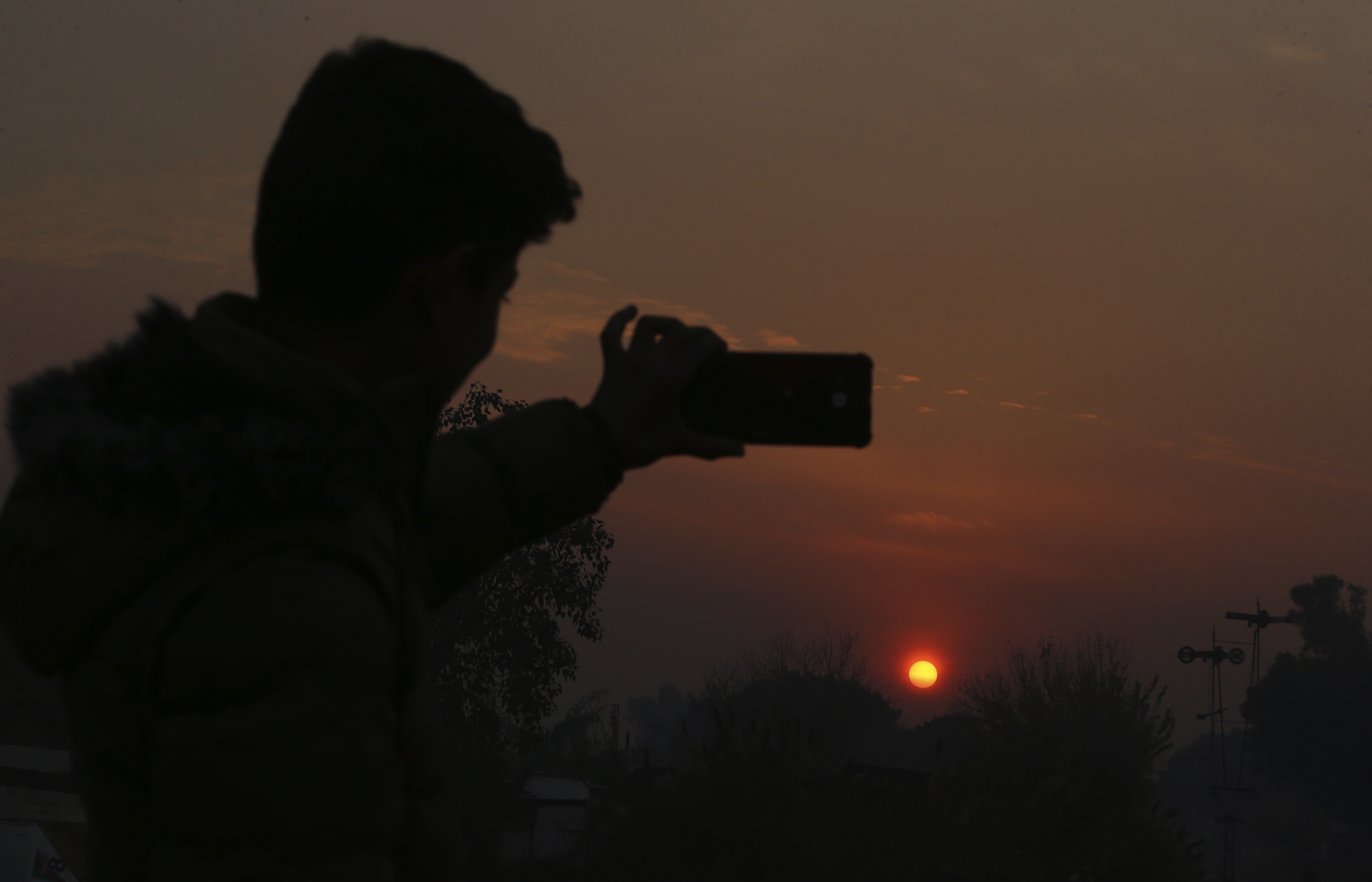 A Pakistani man take a selfie photo while the last sunset of 2024 hangs over the city of Peshawar, Pakistan, Tuesday, Dec. 31, 2024. (AP Photo/Mohammad Sajjad)