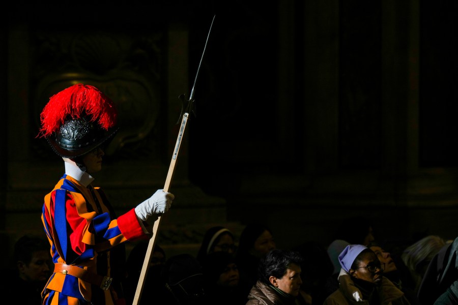 Faithful and a pontifical Swiss guard follow Pope Francis presiding over a mass in St. Peter's Basilica at The Vatican on New Year's Day, Wednesday, Jan. 1, 2025. (AP Photo/Andrew Medichini)