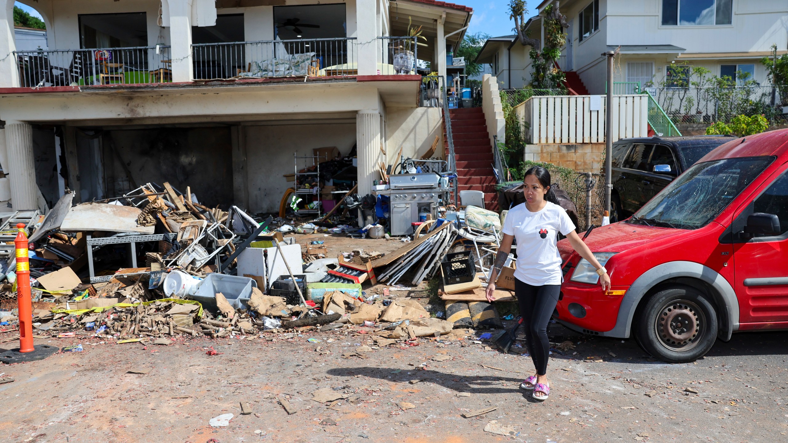 A woman walks in front of the home where a New Year's Eve fireworks explosion killed and injured people, Wednesday, Jan. 1, 2025, in Honolulu. (AP Photo/Marco Garcia)