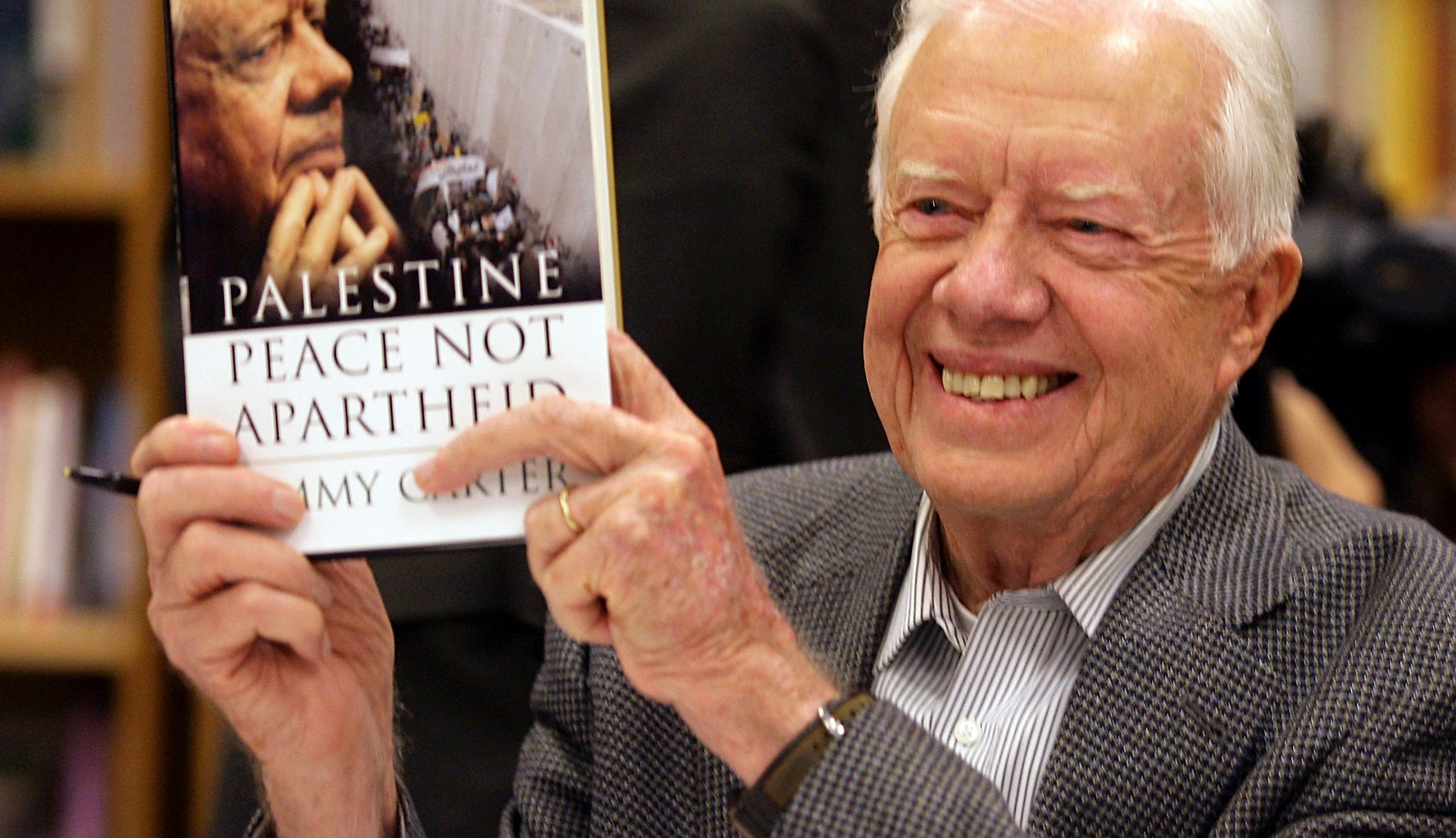 FILE - Former President Jimmy Carter holds a copy of his book, "Palestine: Peace, Not Apartheid," prior to a book signing at the Changing Hands bookstore on Dec. 12, 2006, in Tempe, Ariz. (AP Photo/Paul Connors, File)