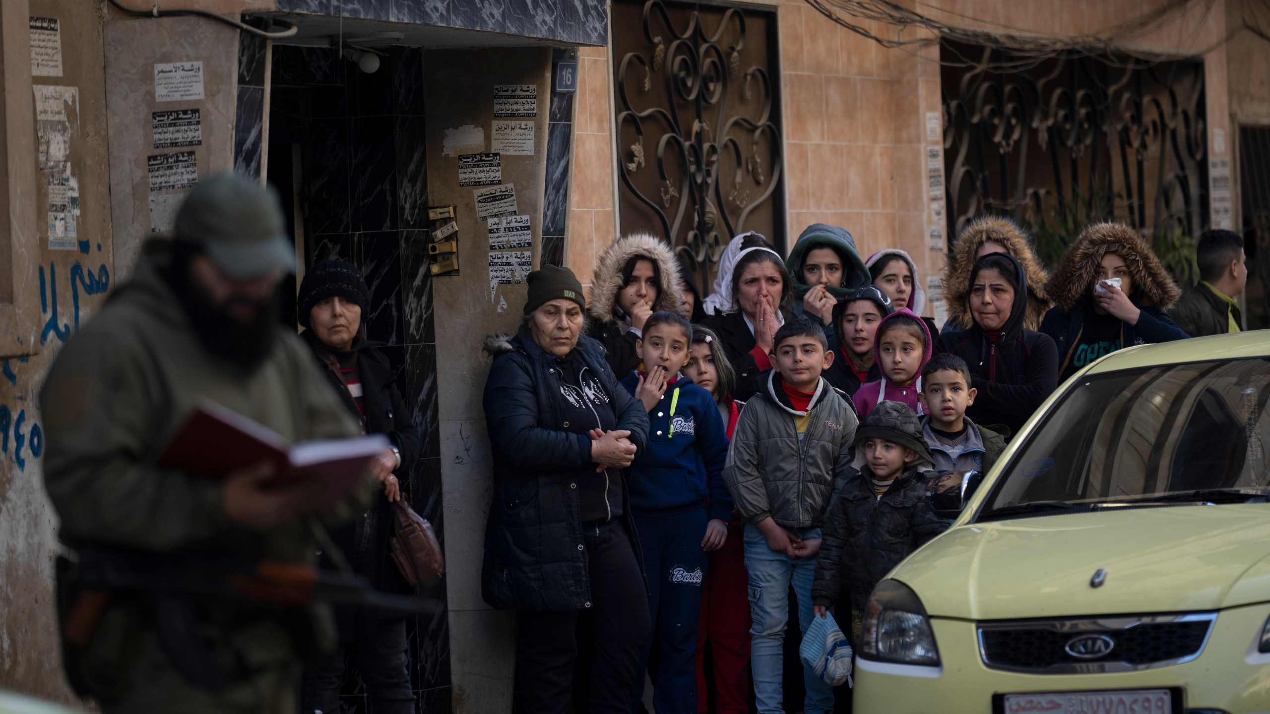 People stand outside their homes as members of the new security forces take part in an operation to detain men suspected of being part of militias or loyalist soldiers of the ousted president Bashar Assad in Homs, Syria, Friday, Jan. 3, 2025. (AP Photo/Leo Correa)