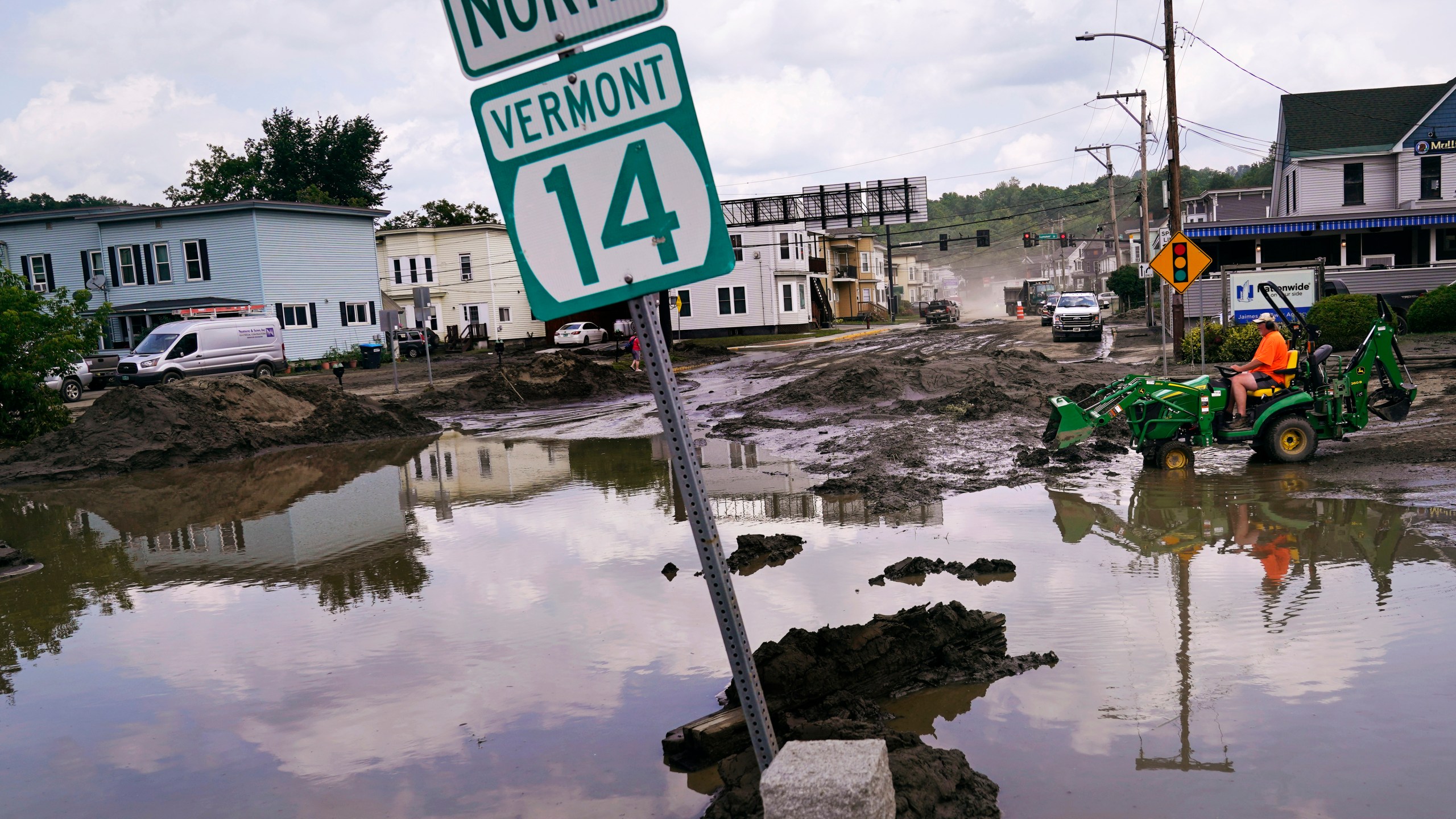 FILE - A small tractor clears water from a business as flood waters block a street, July 12, 2023, in Barre, Vt. (AP Photo/Charles Krupa, File)