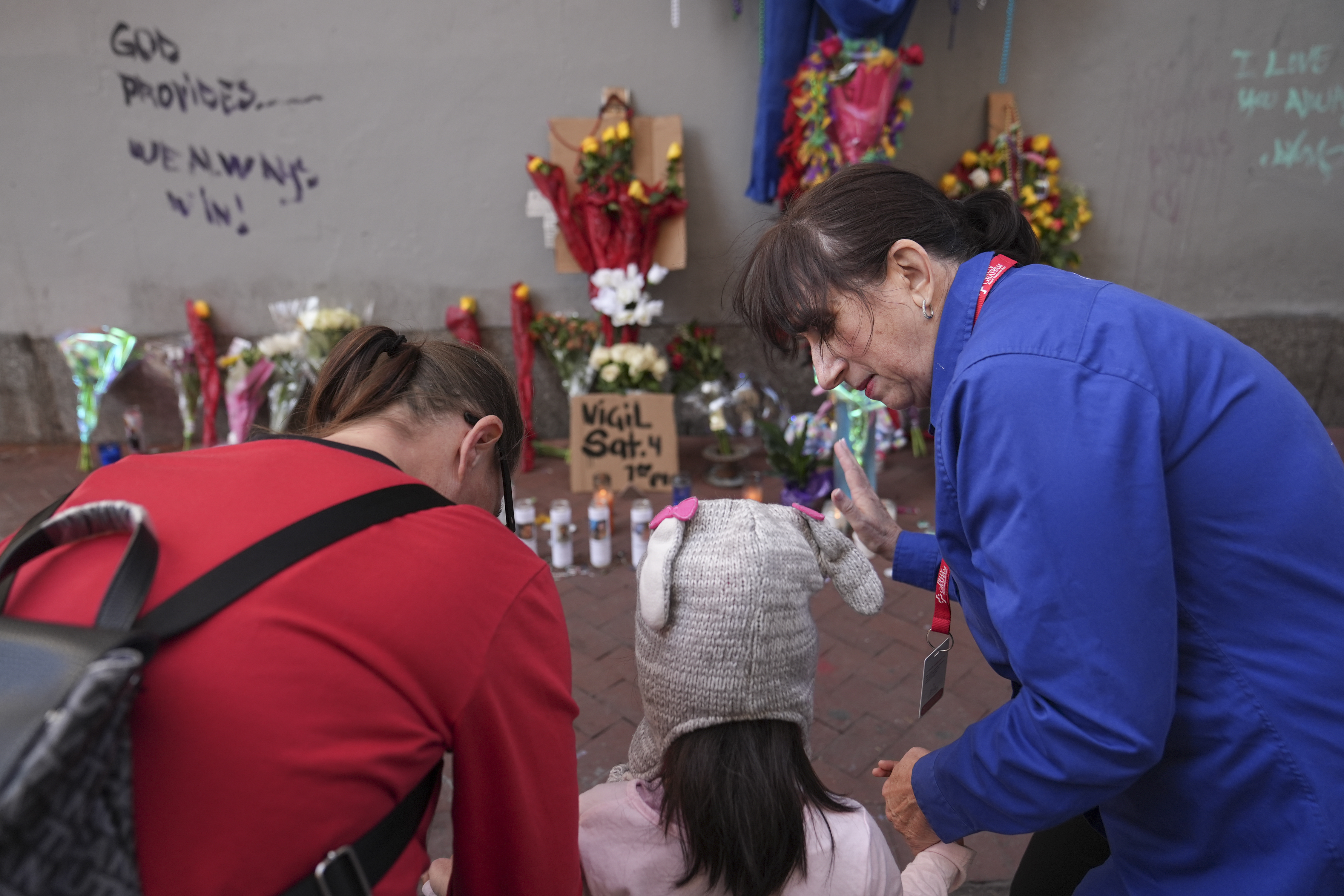 Allyson Tomkins, right, prays with Emily Lara, 5, center, and her grandmother Charity Lara, right, at a memorial to the victims of a deadly truck attack on Bourbon Street in the French Quarter, Friday, Jan. 3, 2025, in New Orleans. (AP Photo/George Walker IV)