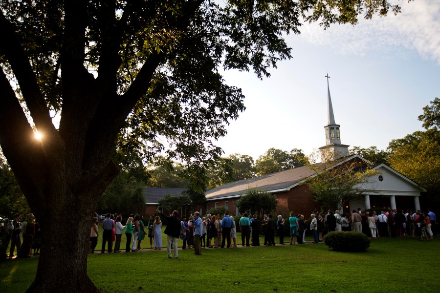 FILE - People wait in line outside Maranatha Baptist Church in Plains, Ga., to get into a Sunday school class taught by former U.S. President Jimmy Carter on Aug. 23, 2015. It was Carter's first lesson since announcing plans for intravenous drug doses and radiation to treat melanoma found in his brain after surgery to remove a tumor from his liver. (AP Photo/David Goldman, File)