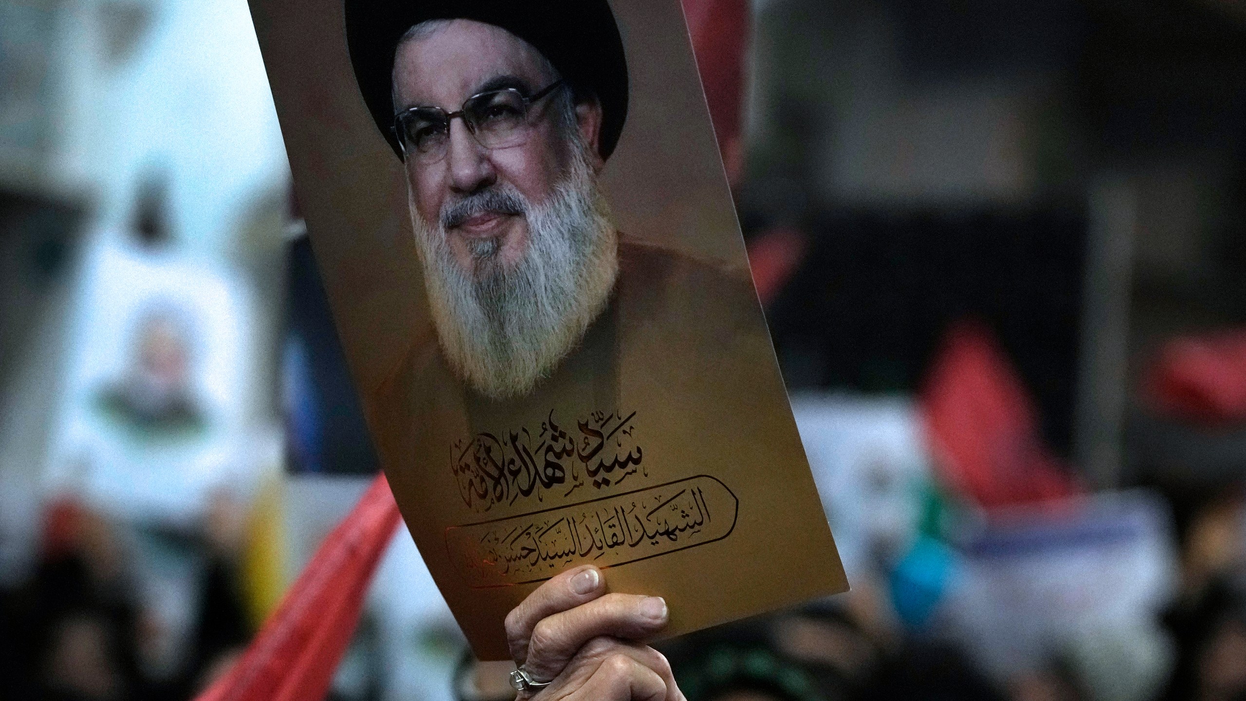 A woman holds up a poster of the slain Hezbollah leader Hassan Nasrallah during a ceremony marking death anniversary of the late commander of the Iran's Revolutionary Guard expeditionary Quds Force, Gen. Qassem Soleimani, who was killed in a U.S. drone attack in 2020, at the Imam Khomeini grand mosque in Tehran, Iran, Thursday, Jan. 2, 2025. (AP Photo/Vahid Salemi)