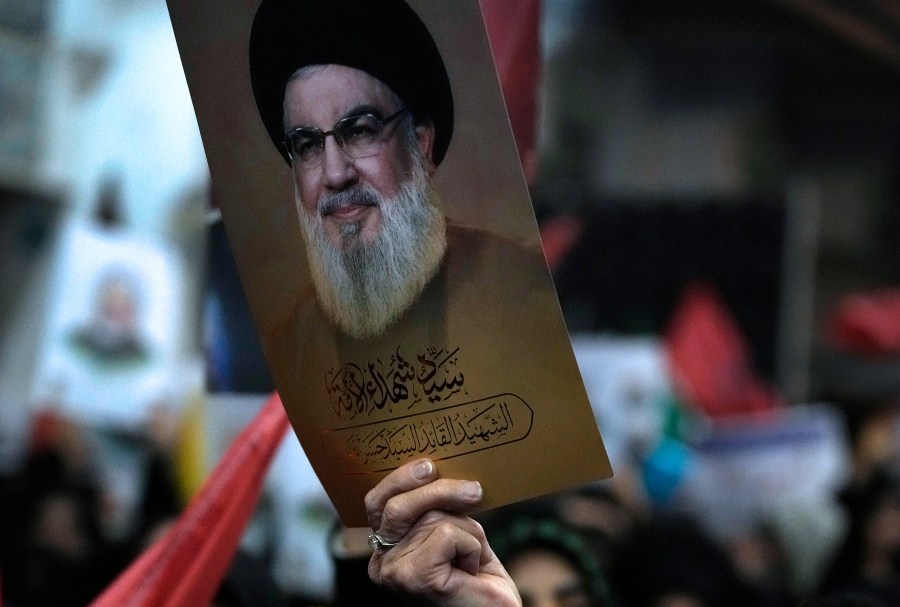 A woman holds up a poster of the slain Hezbollah leader Hassan Nasrallah during a ceremony marking death anniversary of the late commander of the Iran's Revolutionary Guard expeditionary Quds Force, Gen. Qassem Soleimani, who was killed in a U.S. drone attack in 2020, at the Imam Khomeini grand mosque in Tehran, Iran, Thursday, Jan. 2, 2025. (AP Photo/Vahid Salemi)