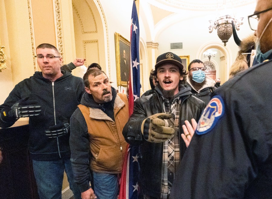 FILE - Violent protesters loyal to President Donald Trump, including Kevin Seefried, center, holding a Confederate battle flag, are confronted by U.S. Capitol Police officers outside the Senate Chamber inside the Capitol, Jan. 6, 2021 in Washington. (AP Photo/Manuel Balce Ceneta, File)