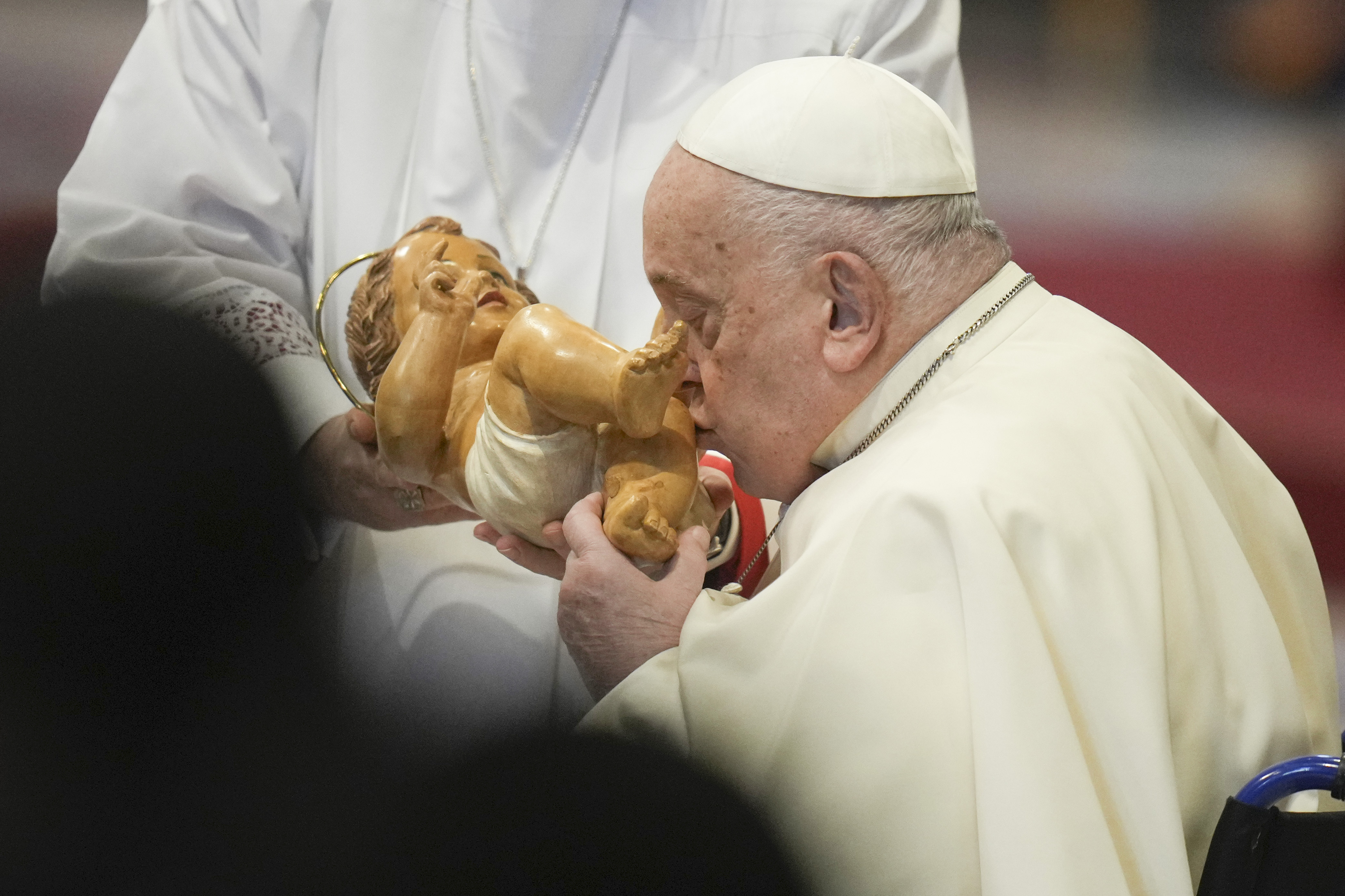 Pope Francis kisses the baby Jesus as he presides over an Epiphany mass in St.Peter's Basilica, at the Vatican, Monday, Jan. 6, 2025. (AP Photo/Alessandra Tarantino)