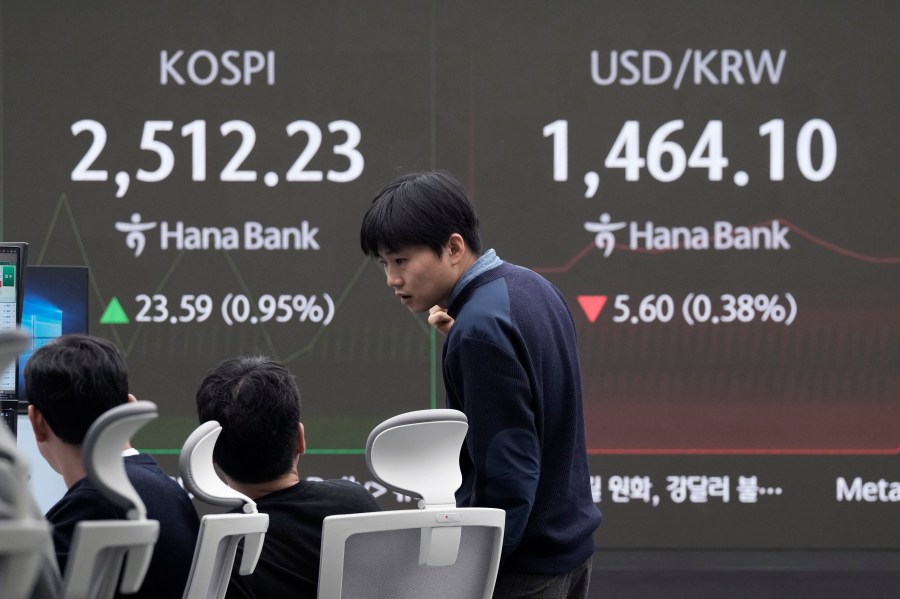 A currency trader works near a screen showing the Korea Composite Stock Price Index (KOSPI), left, and the foreign exchange rate between U.S. dollar and South Korean won at the foreign exchange dealing room of the KEB Hana Bank headquarters in Seoul, South Korea, Tuesday, Jan. 7, 2025. (AP Photo/Ahn Young-joon)