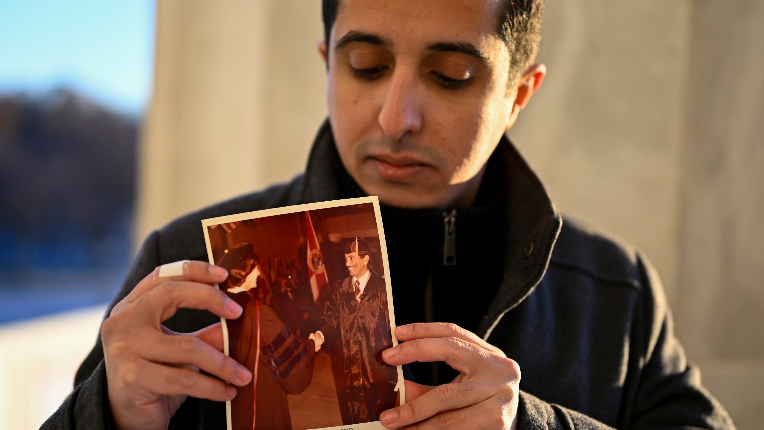 Ibrahim Almadi holds a photo of his father Saad Almadi graduating from college in 1984, in Washington Monday, Dec. 23, 2024. Saad Almadi, a dual U.S.-Saudi citizen was jailed for social media posts critical of the kingdom's crown prince. He was released from a Saudi prison in March 2023 and banned from returning to his home in south Florida. (AP Photo/John McDonnell)