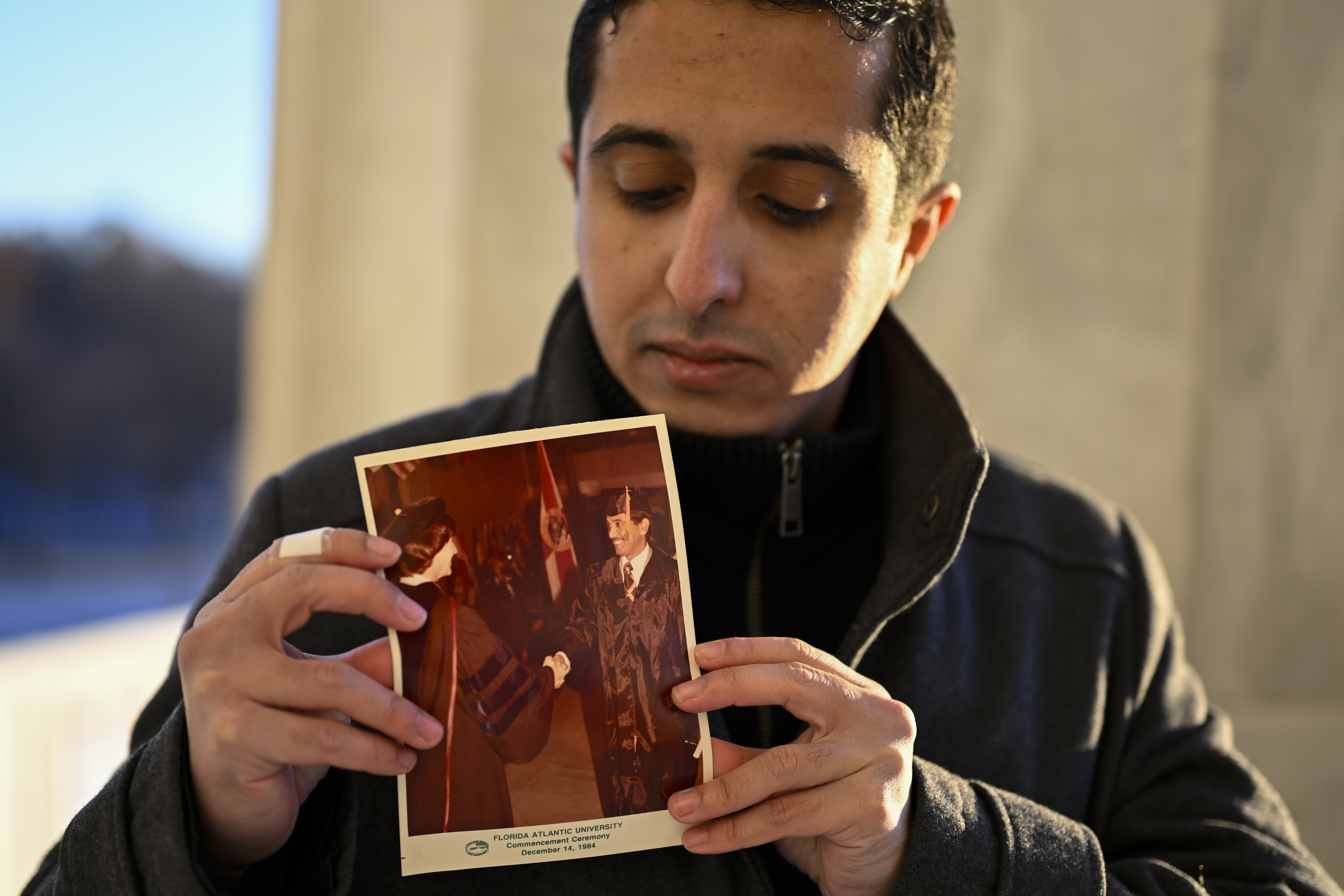 Ibrahim Almadi holds a photo of his father Saad Almadi graduating from college in 1984, in Washington Monday, Dec. 23, 2024. Saad Almadi, a dual U.S.-Saudi citizen was jailed for social media posts critical of the kingdom's crown prince. He was released from a Saudi prison in March 2023 and banned from returning to his home in south Florida. (AP Photo/John McDonnell)