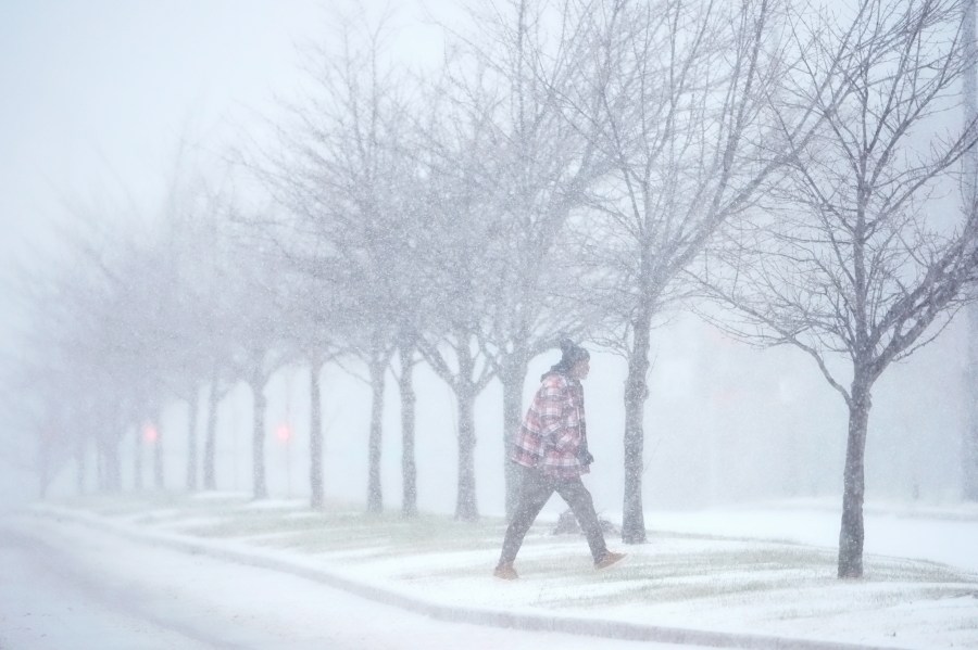 A person crosses a street as heavy snow falls Sunday, Jan. 5, 2025, in St. Louis. (AP Photo/Jeff Roberson)