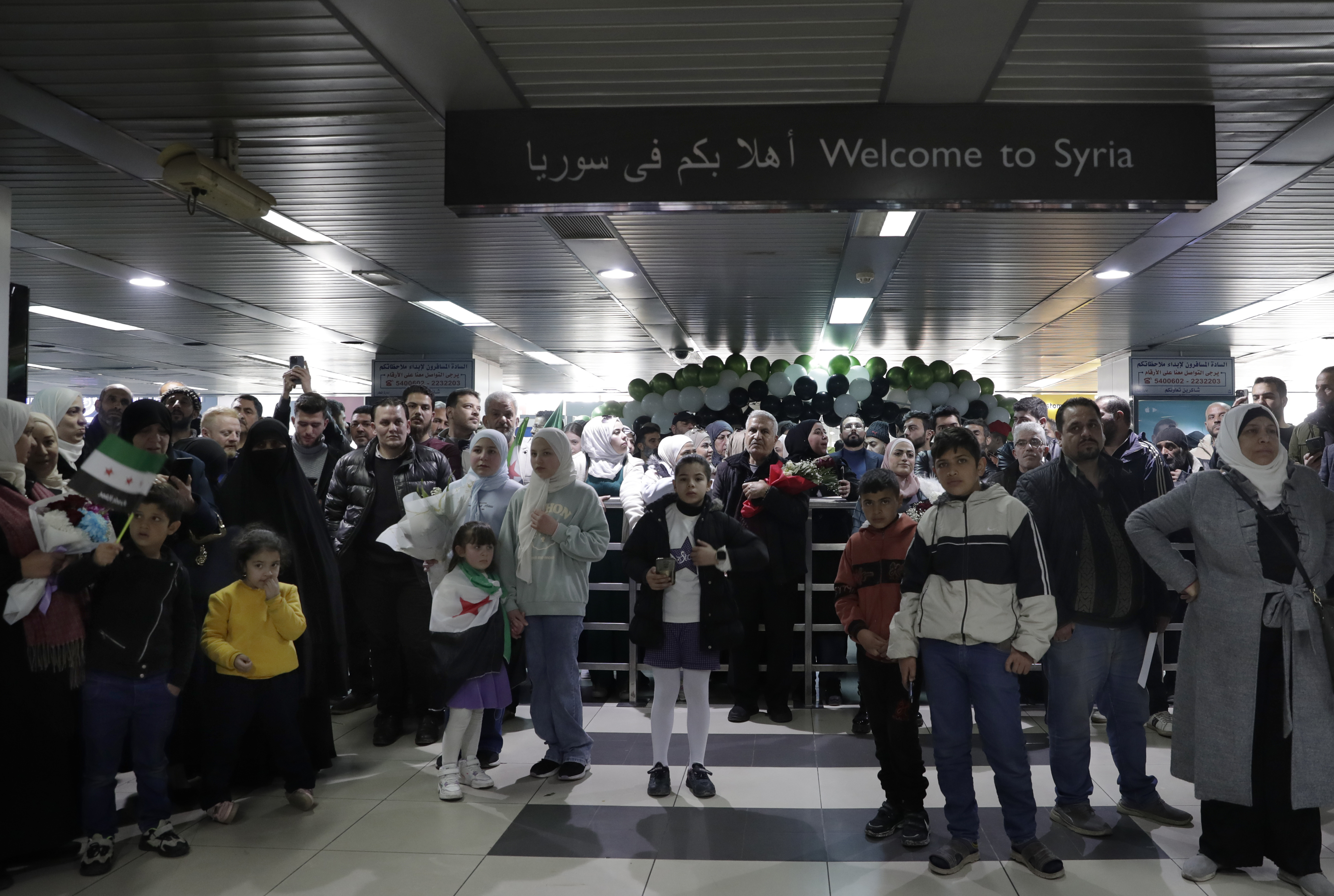 People wait to receive their relatives at the arrival terminal, after a first international commercial flight since the fall of former Syrian President Bashar Assad landed at Damascus international airport, in Damascus, Syria, Tuesday, Jan. 7, 2025. (AP Photo/Omar Sanadiki)