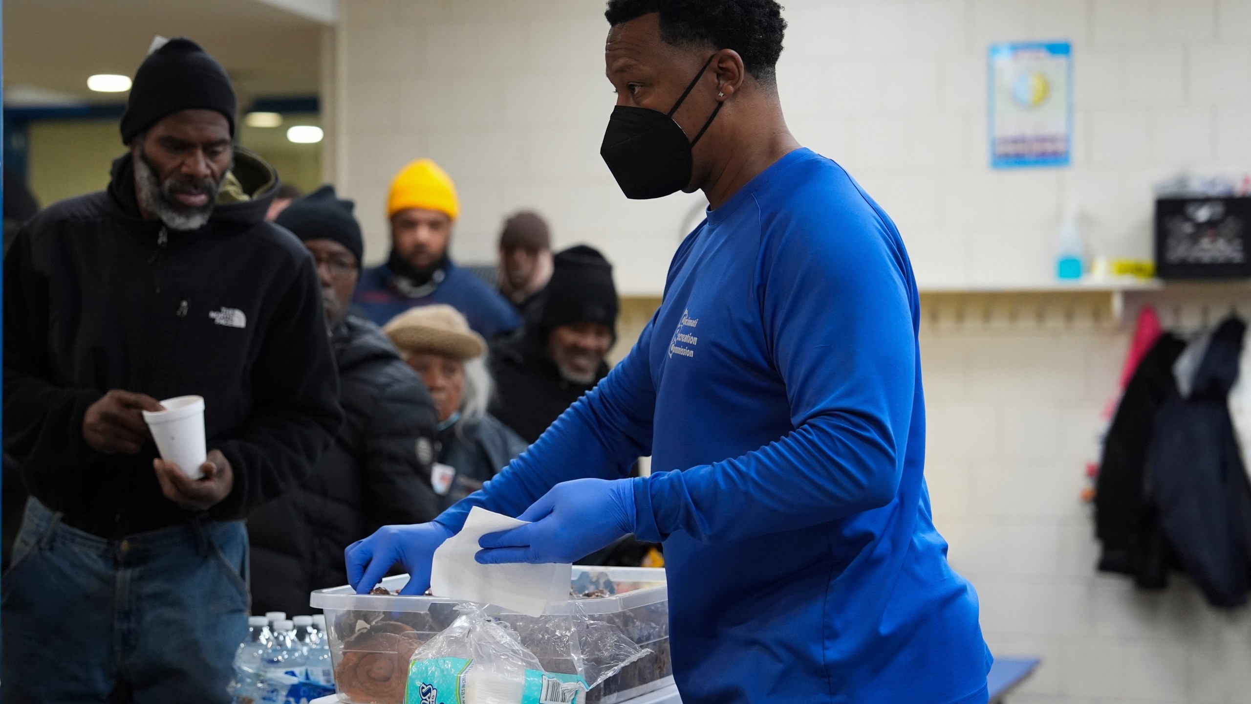 Idris Mills, right, hands out food to patrons inside a daytime warming shelter, Tuesday, Jan. 7, 2025, in Cincinnati. (AP Photo/Joshua A. Bickel)