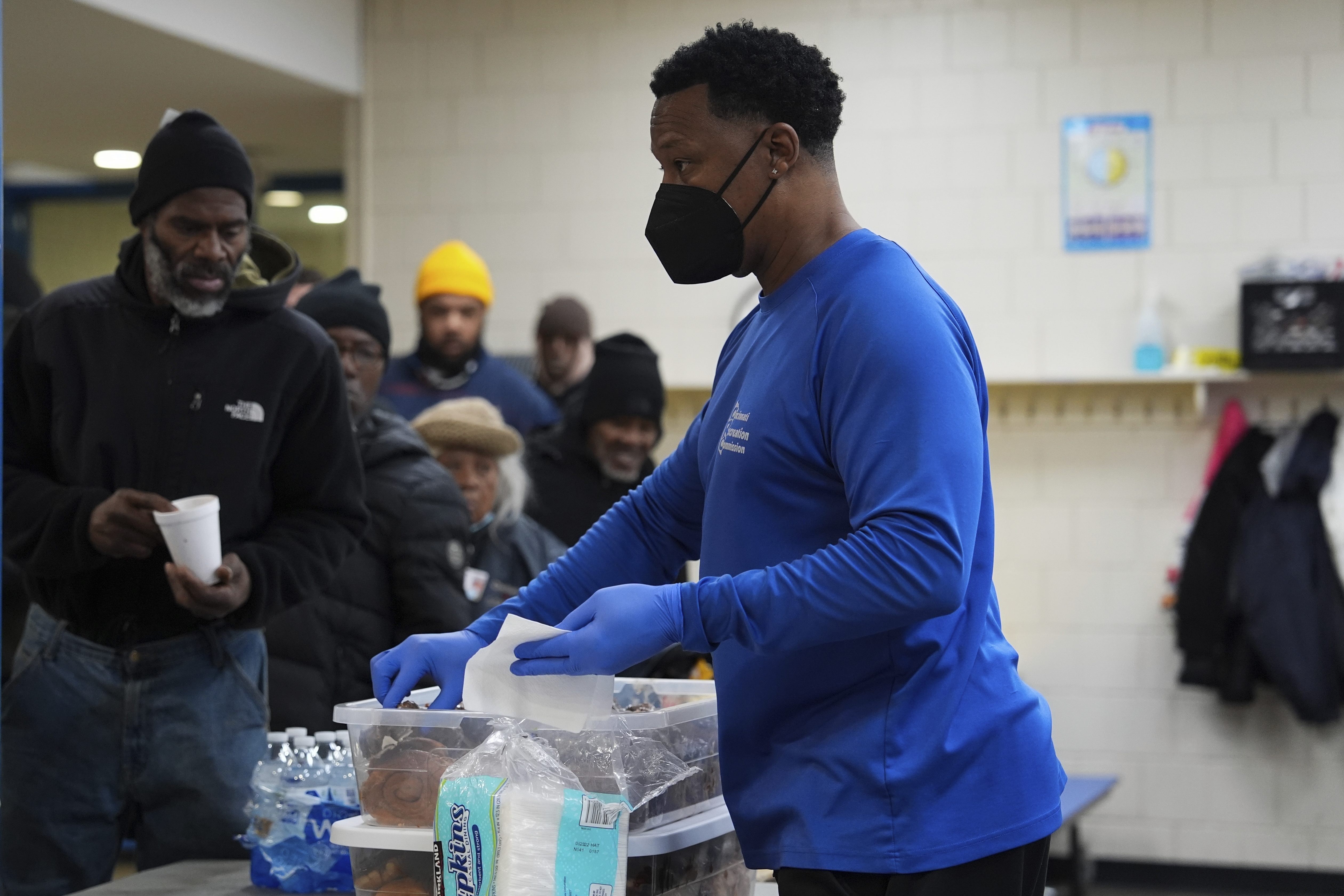 Idris Mills, right, hands out food to patrons inside a daytime warming shelter, Tuesday, Jan. 7, 2025, in Cincinnati. (AP Photo/Joshua A. Bickel)