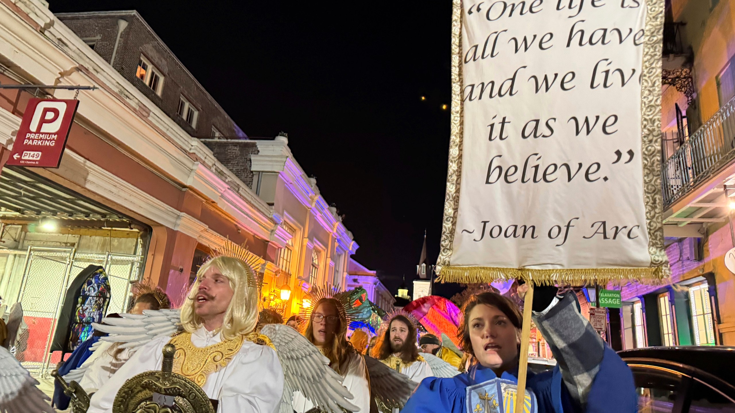 Marchers in the Joan of Arc parade on Monday, Jan. 6, 2025, in New Orleans, hold aloft a banner with a quote from the French saint. (AP Photo/Jack Brook)