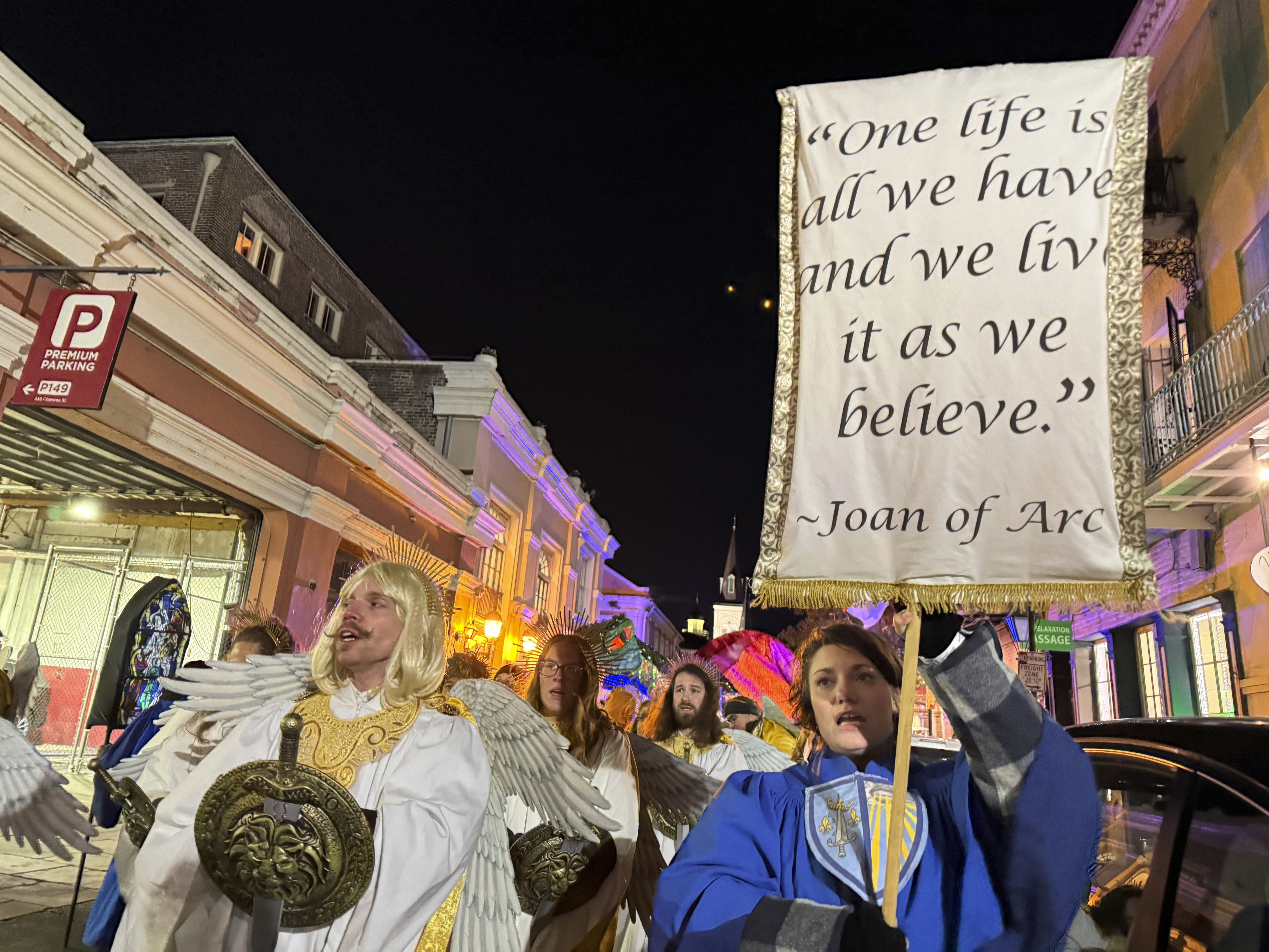 Marchers in the Joan of Arc parade on Monday, Jan. 6, 2025, in New Orleans, hold aloft a banner with a quote from the French saint. (AP Photo/Jack Brook)