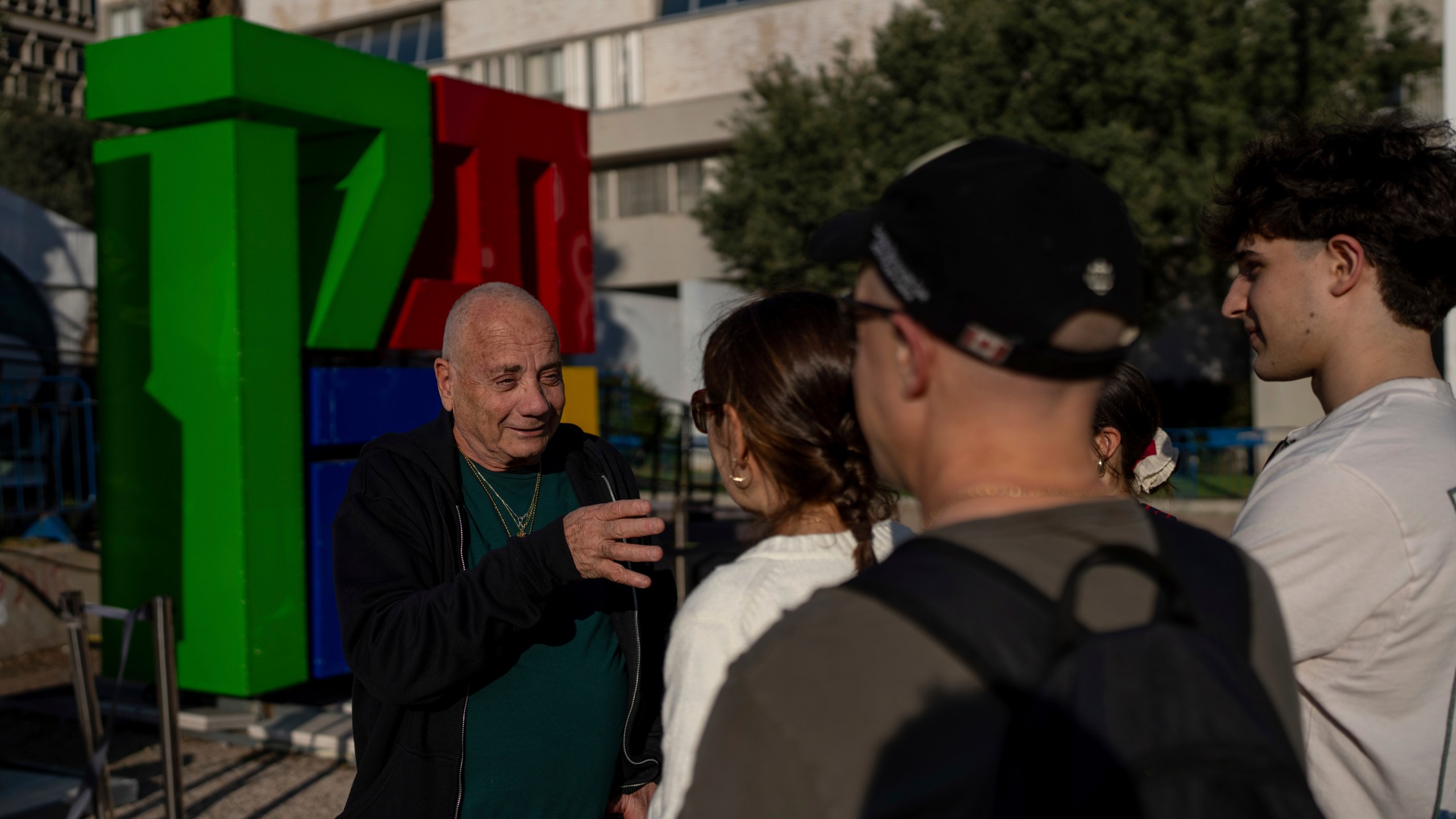 Luis Har, who was rescued from Hamas captivity in an Israeli raid last year, talks with visitors to the Hostages Square in Tel Aviv, Israel, Monday, Jan. 6, 2025. (AP Photo/Ohad Zwigenberg)